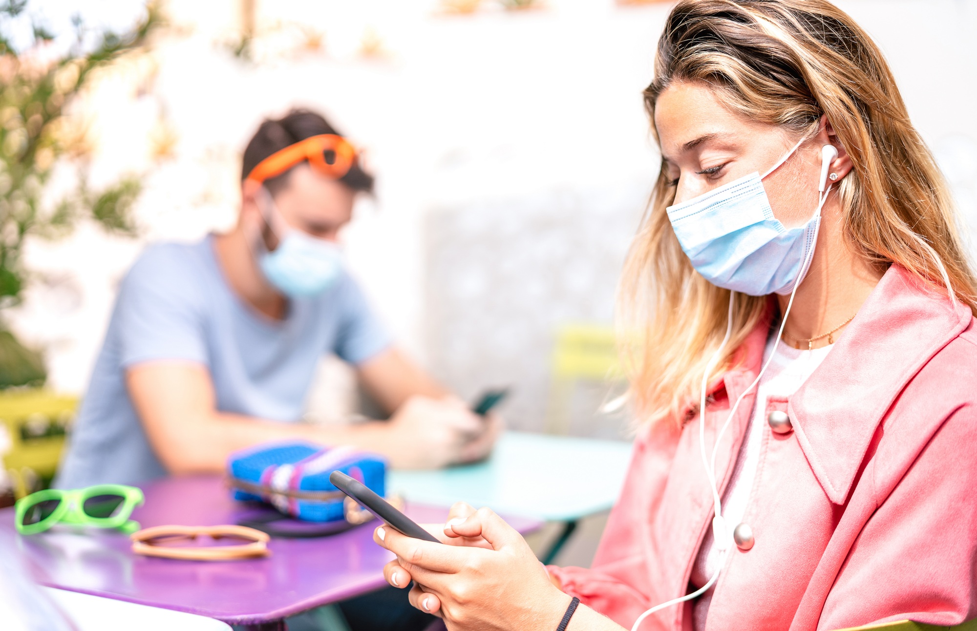 Young woman with earphones using tracking app on mobile smart phone