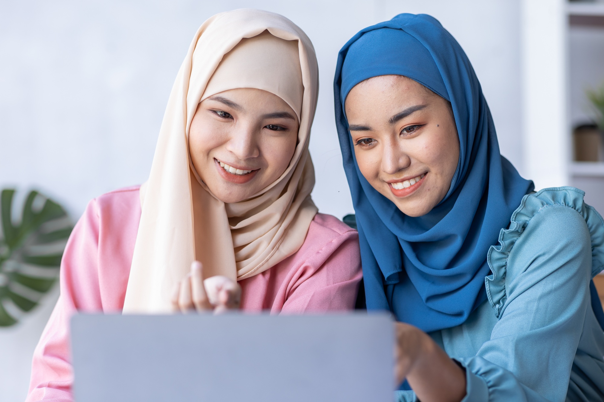 Two Young muslim business women point to graphs and charts to analyze market data, balance sheet, ac