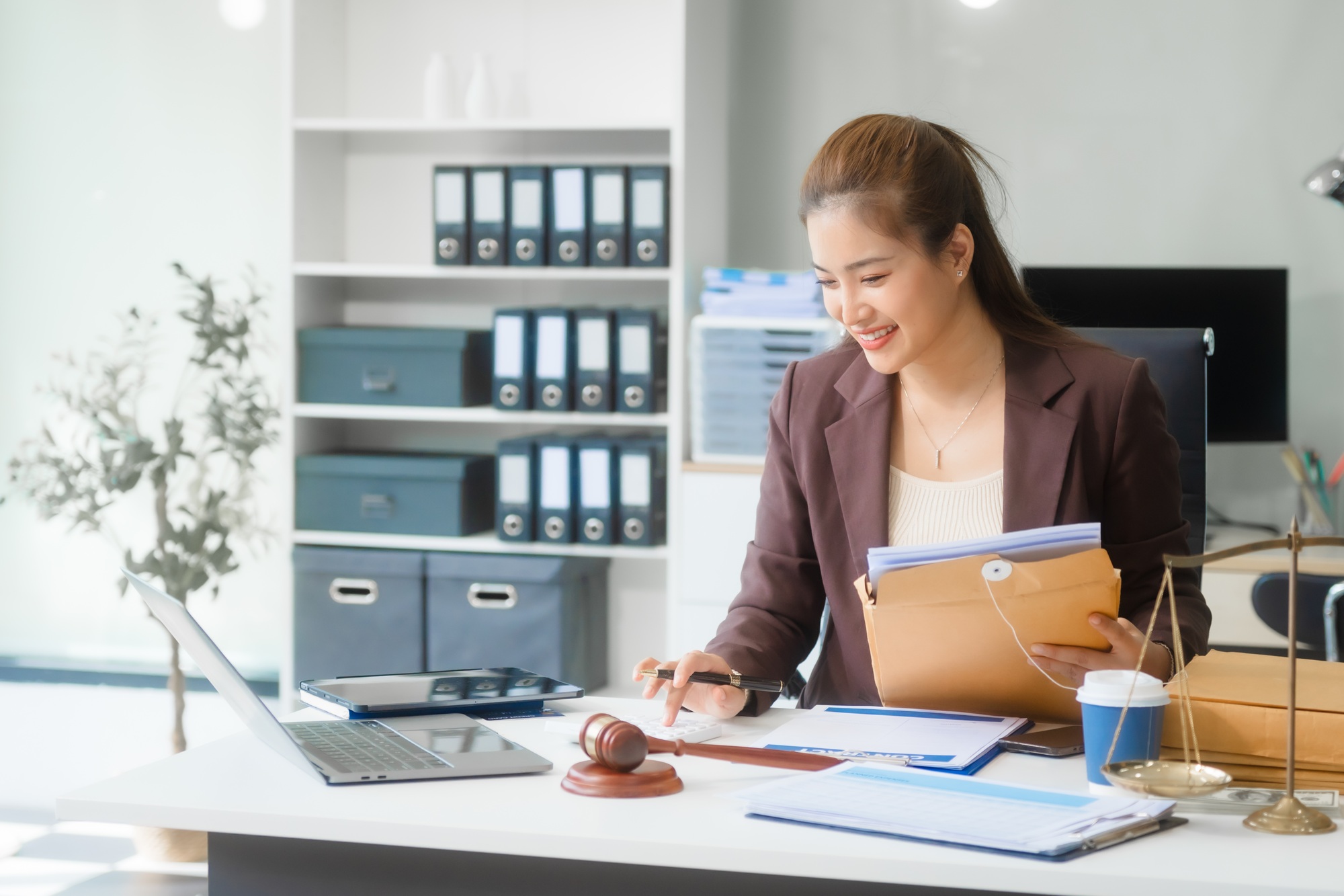 Asian businesswoman in formal attire works on laptop, on corporate law and marketing strategy.
