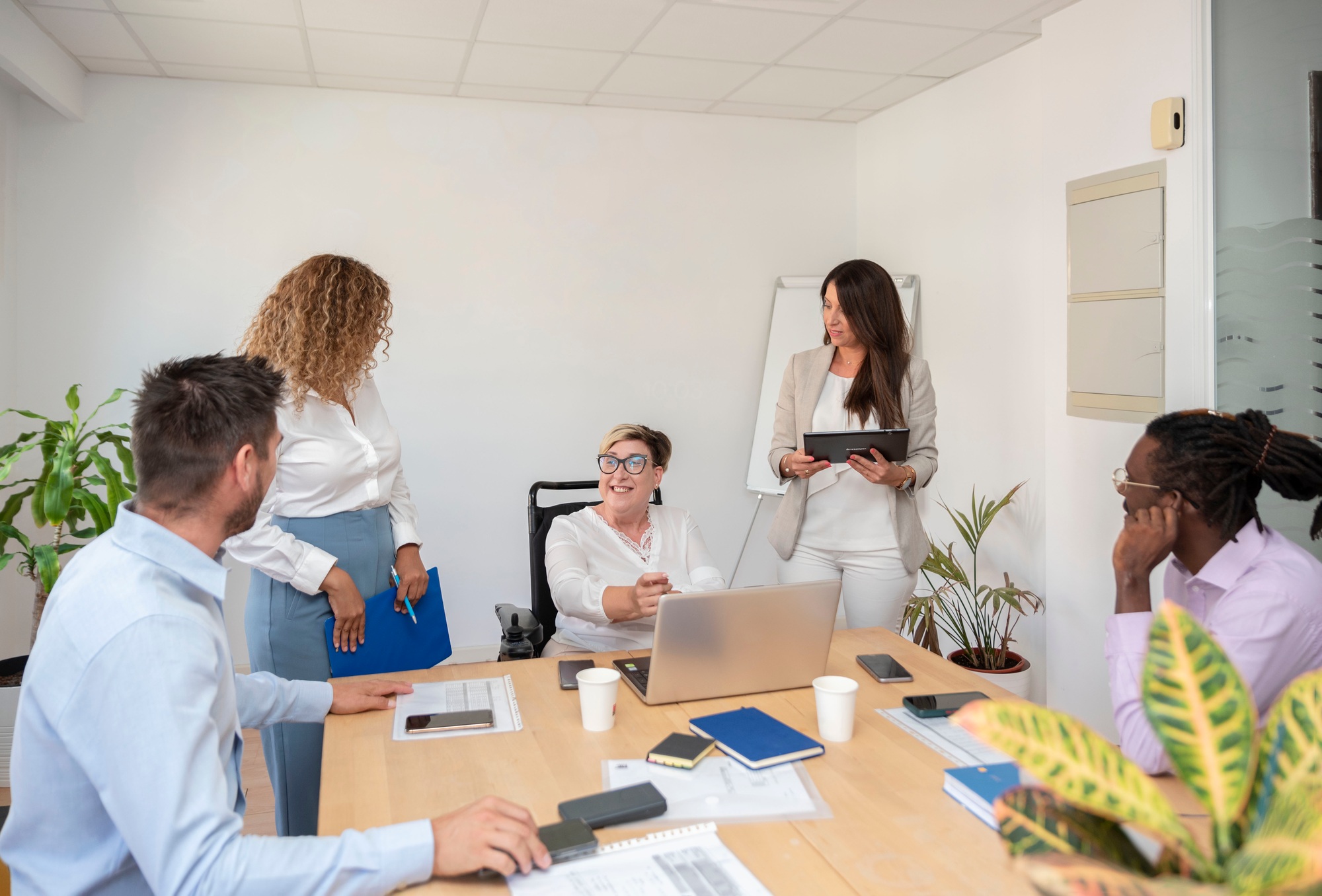 a businesswoman in a wheelchair with a disability leads a meeting with a multiracial entrepreneurs