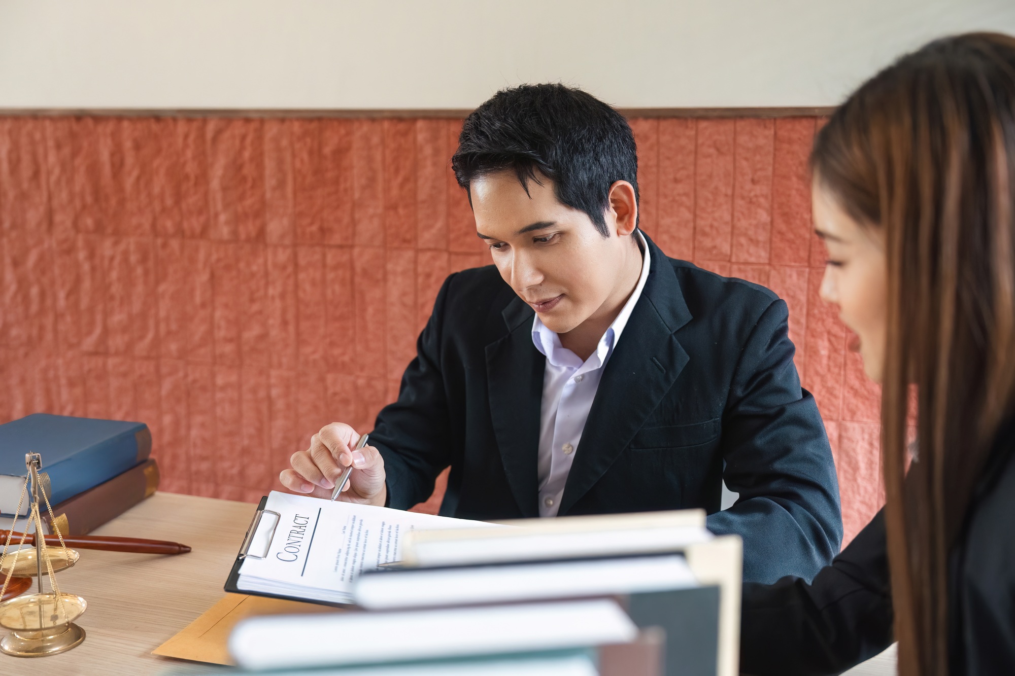 A client focusing on important legal agreements with guidance from a lawyer.