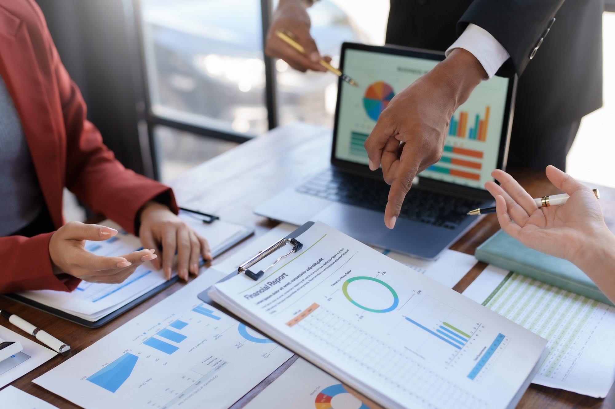 A group of business professionals engaged in analyzing financial reports and data on a laptop