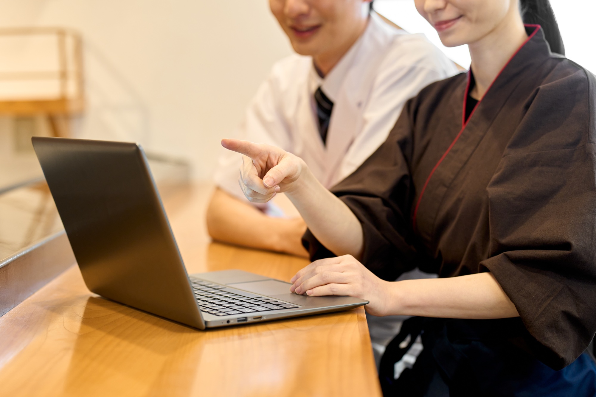A Japanese restaurant employee happily looking at a computer