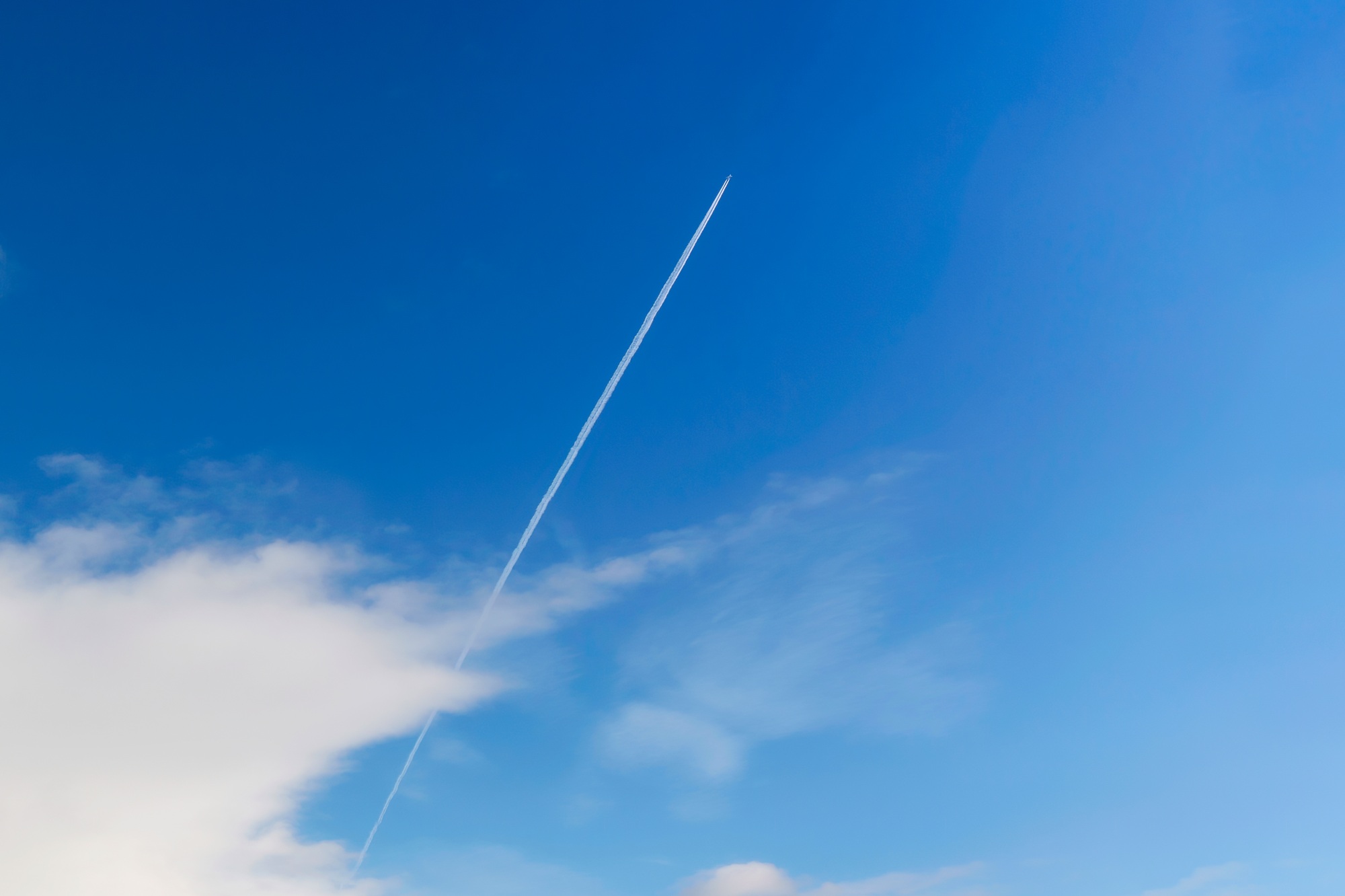 A private jet plane flying with contrail or vapor trails on blue sky