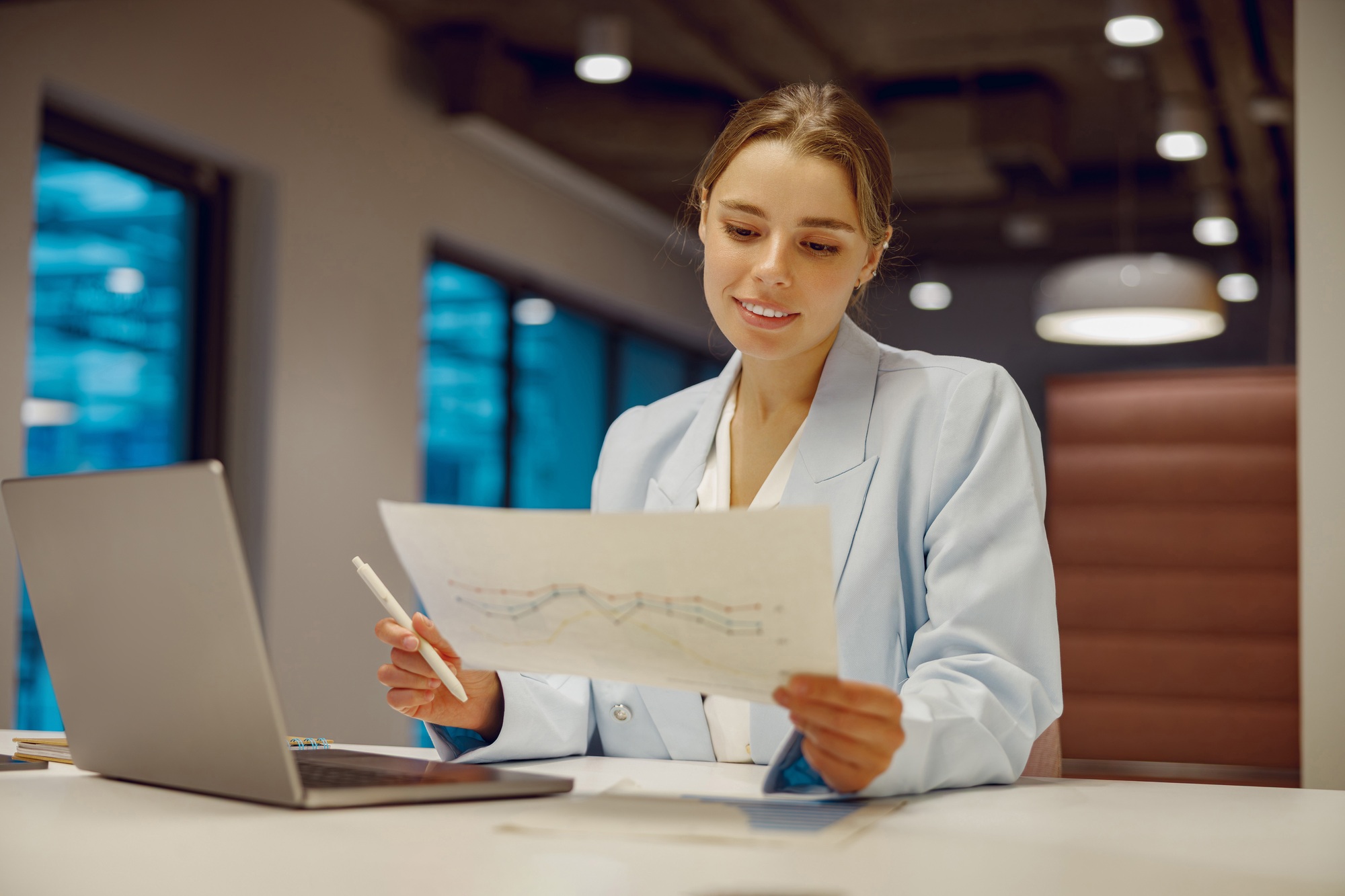 A professional businesswoman carefully analyzing the latest market trends in a modern office space