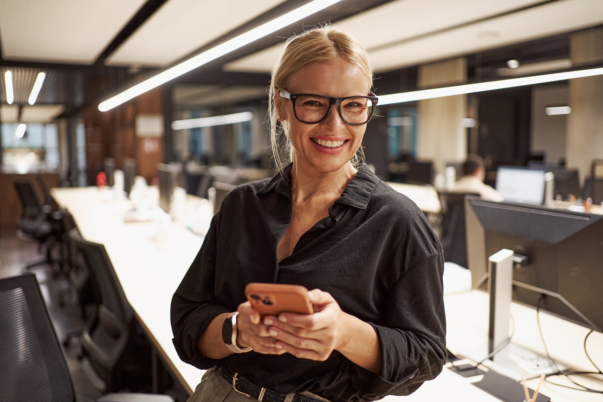 A smiling professional woman skillfully using her smartphone in a contemporary office environment