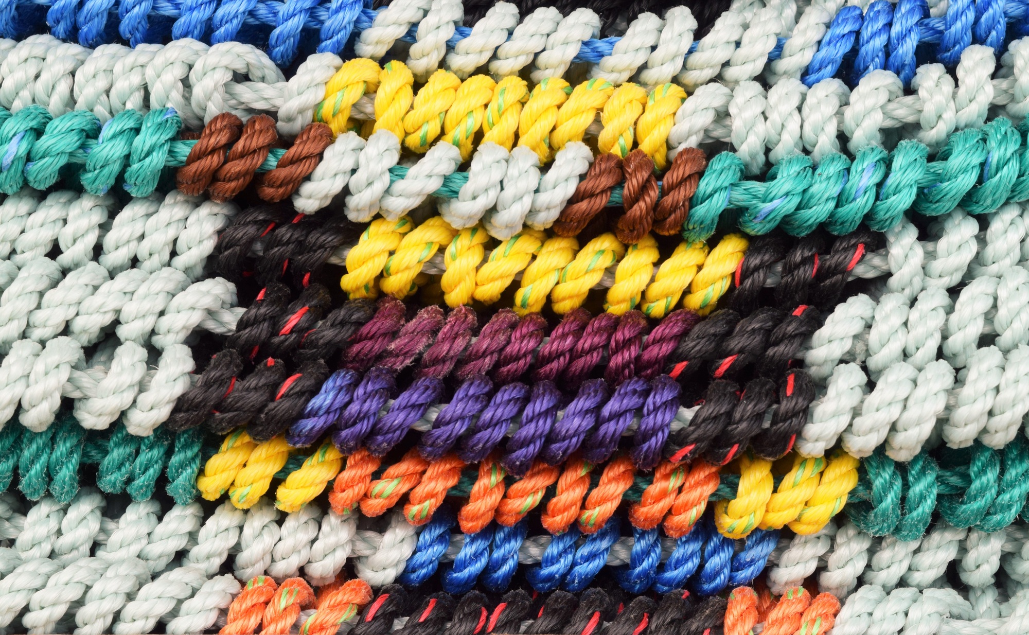 A stack of colorful woven rugs for sale