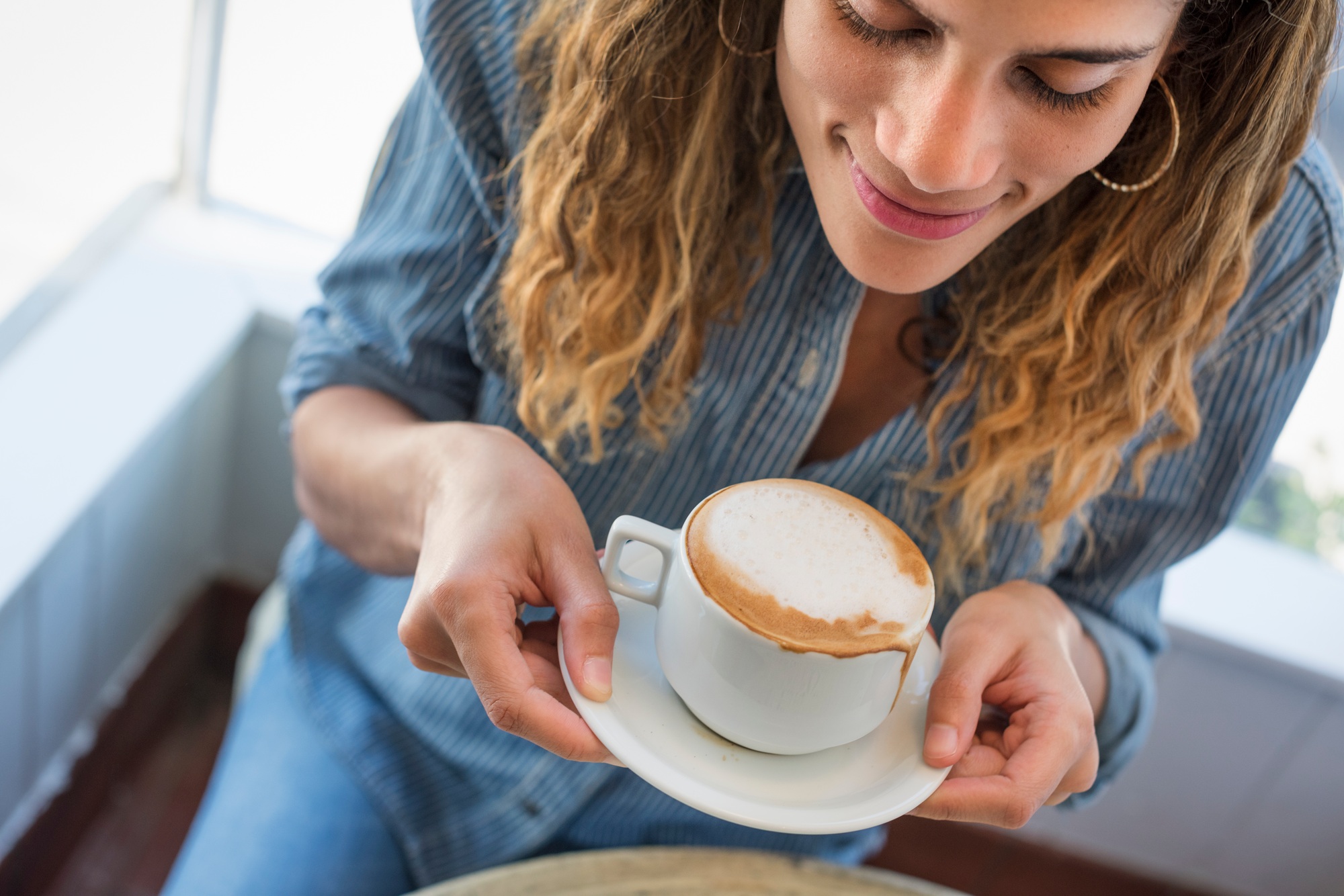 A woman holding a coffee cup at a coffee shop.