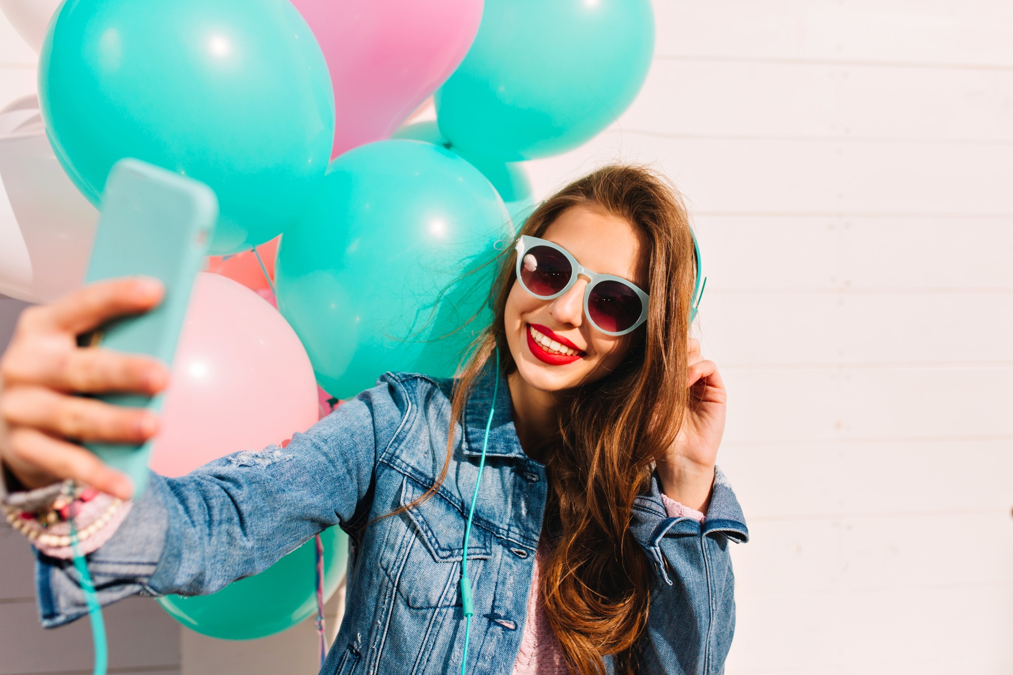 Adorable young woman with long hair makes new photo for facebook profile while having fun at friend'