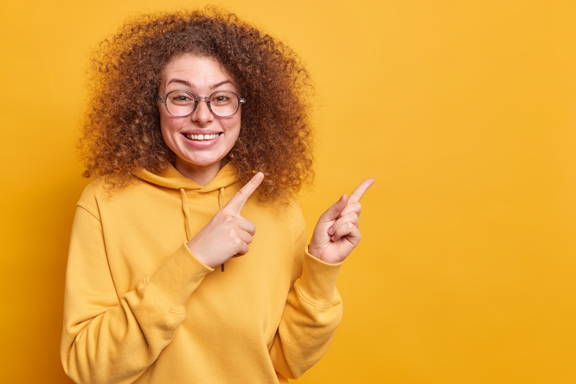 Advertising concept. Cheerful Afro American woman looks happily at logo gives advice shows advertise