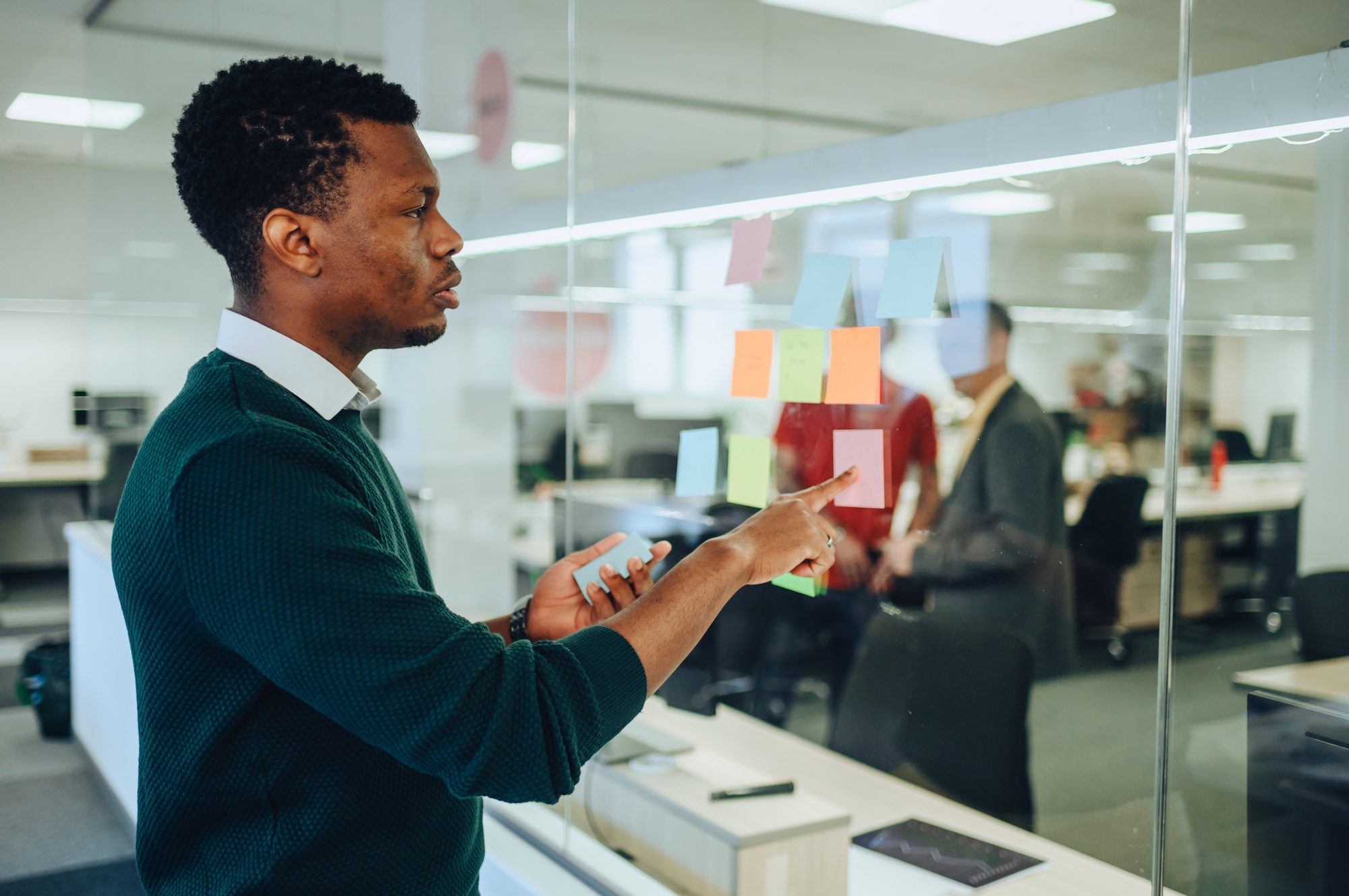 African american businessman is following tasks and goals on a sticky notes.