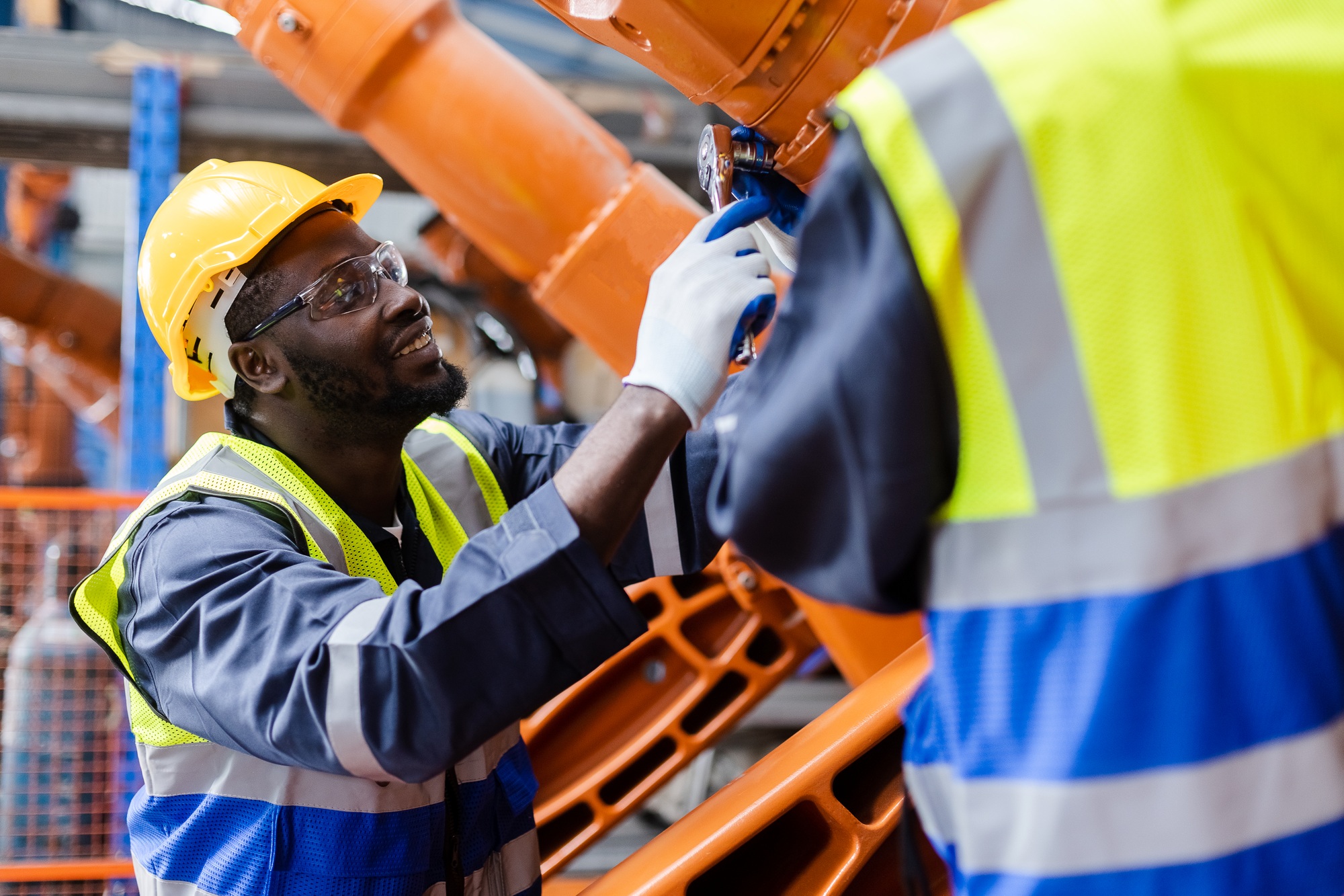African American man engineer standing at automation robot arms machine in factory.