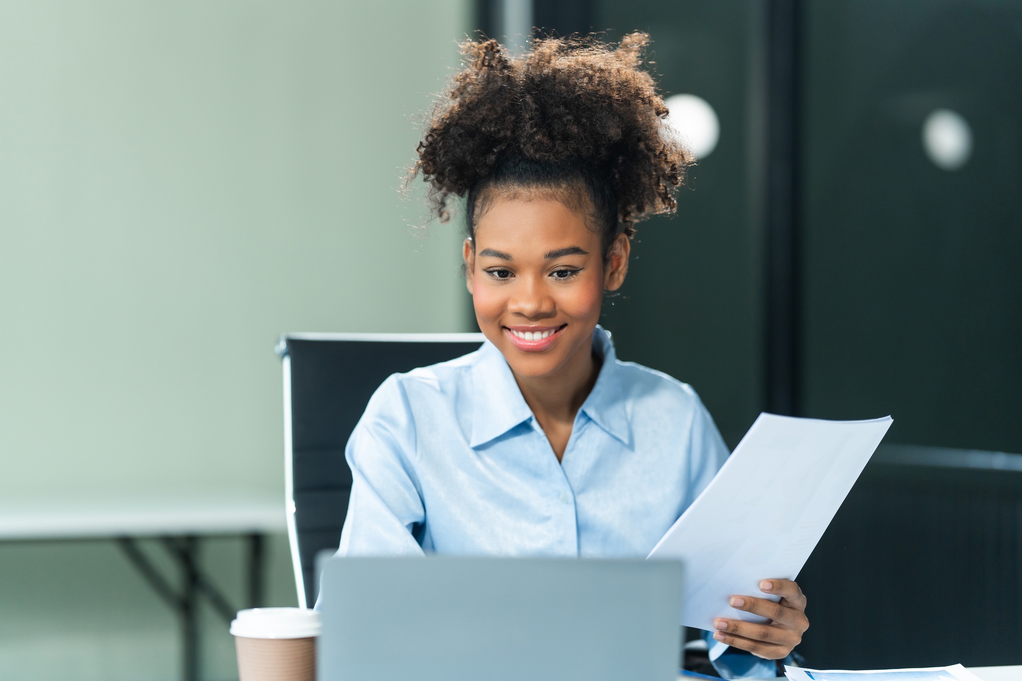 Analyzing business charts A4, a young African American woman in a blue formal shirt afro brown hair