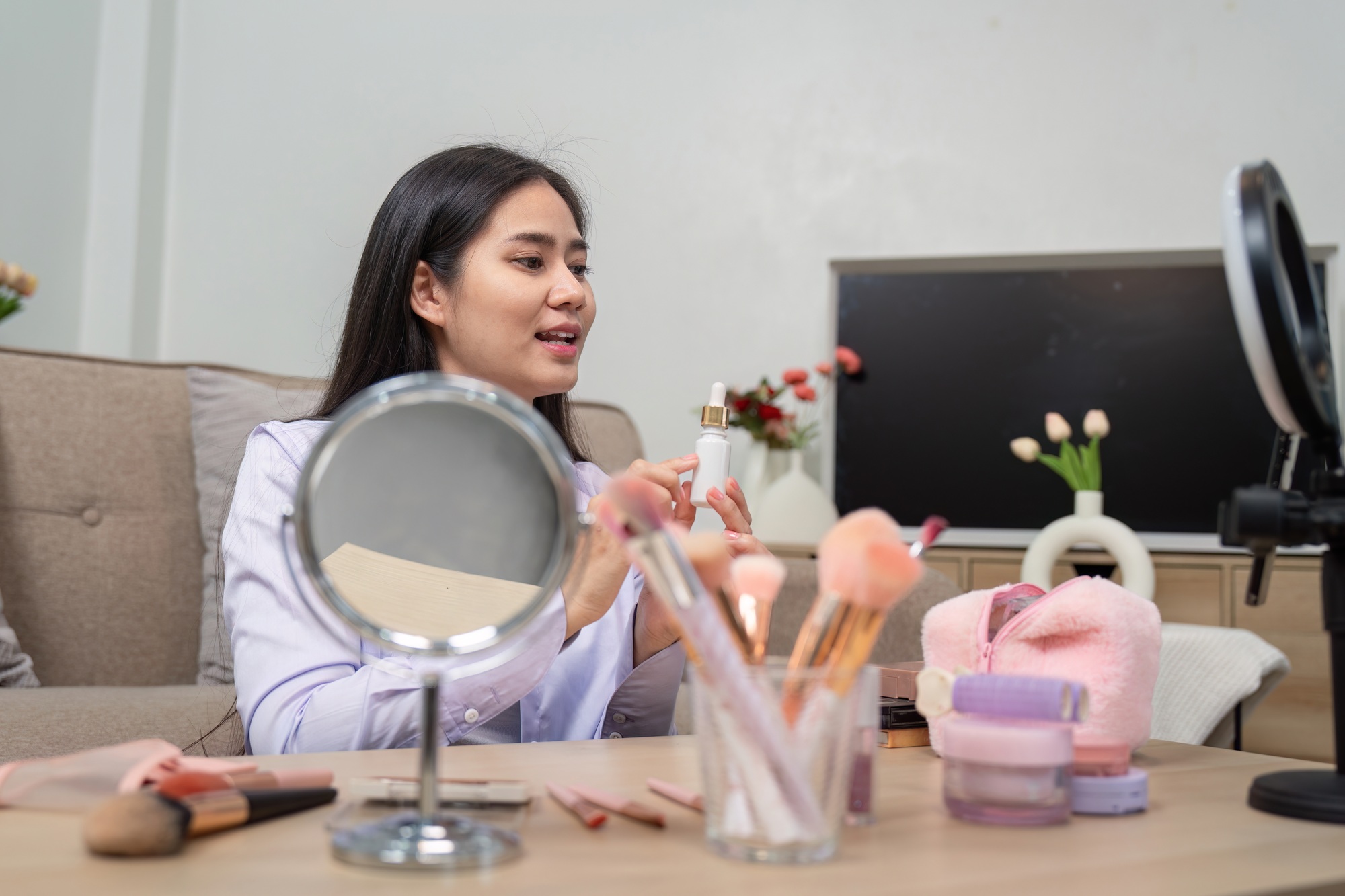 Asian beauty influencer applying makeup during video tutorial