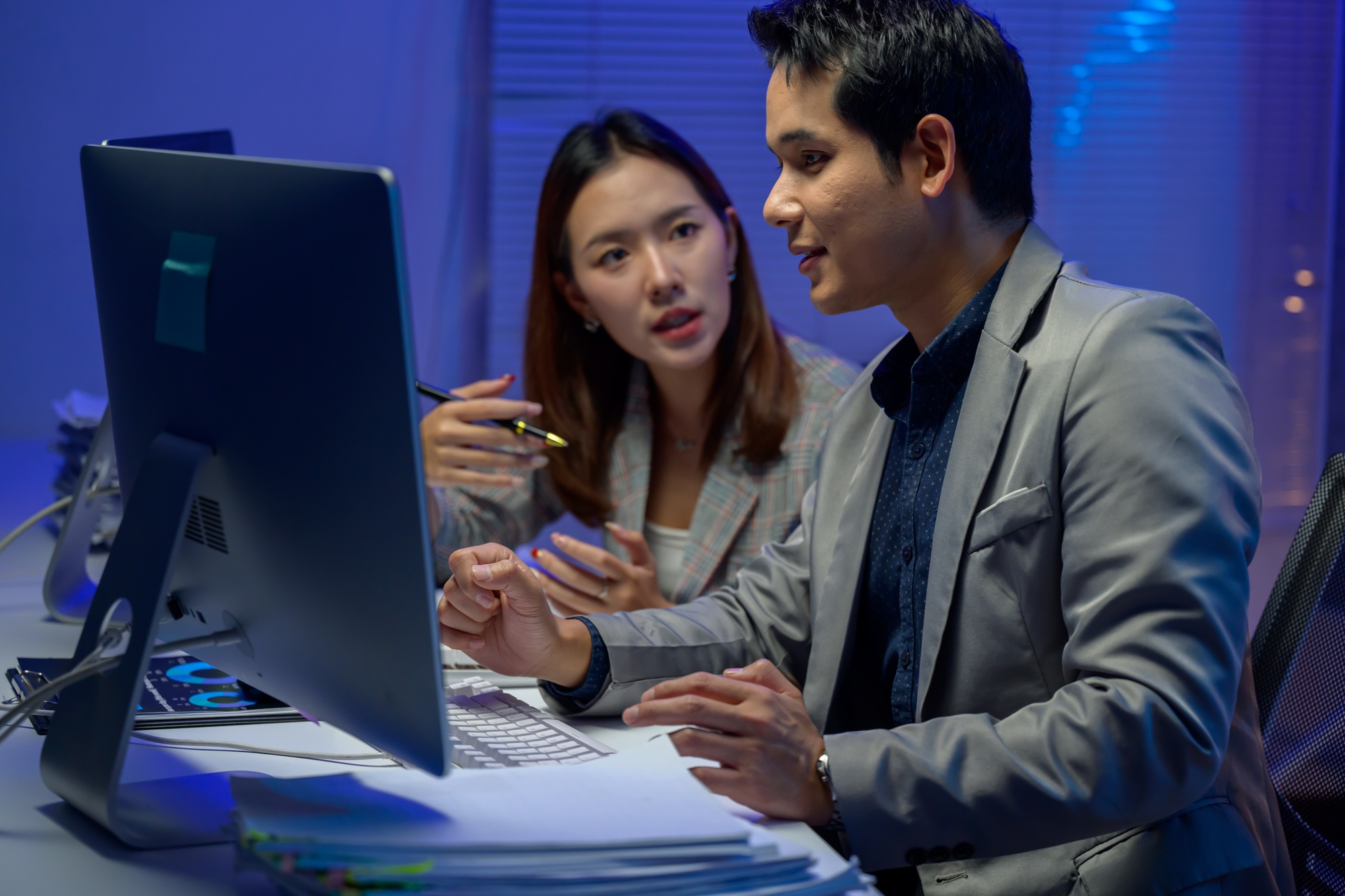 Asian business team working late night analyzing financial data on desktop computer