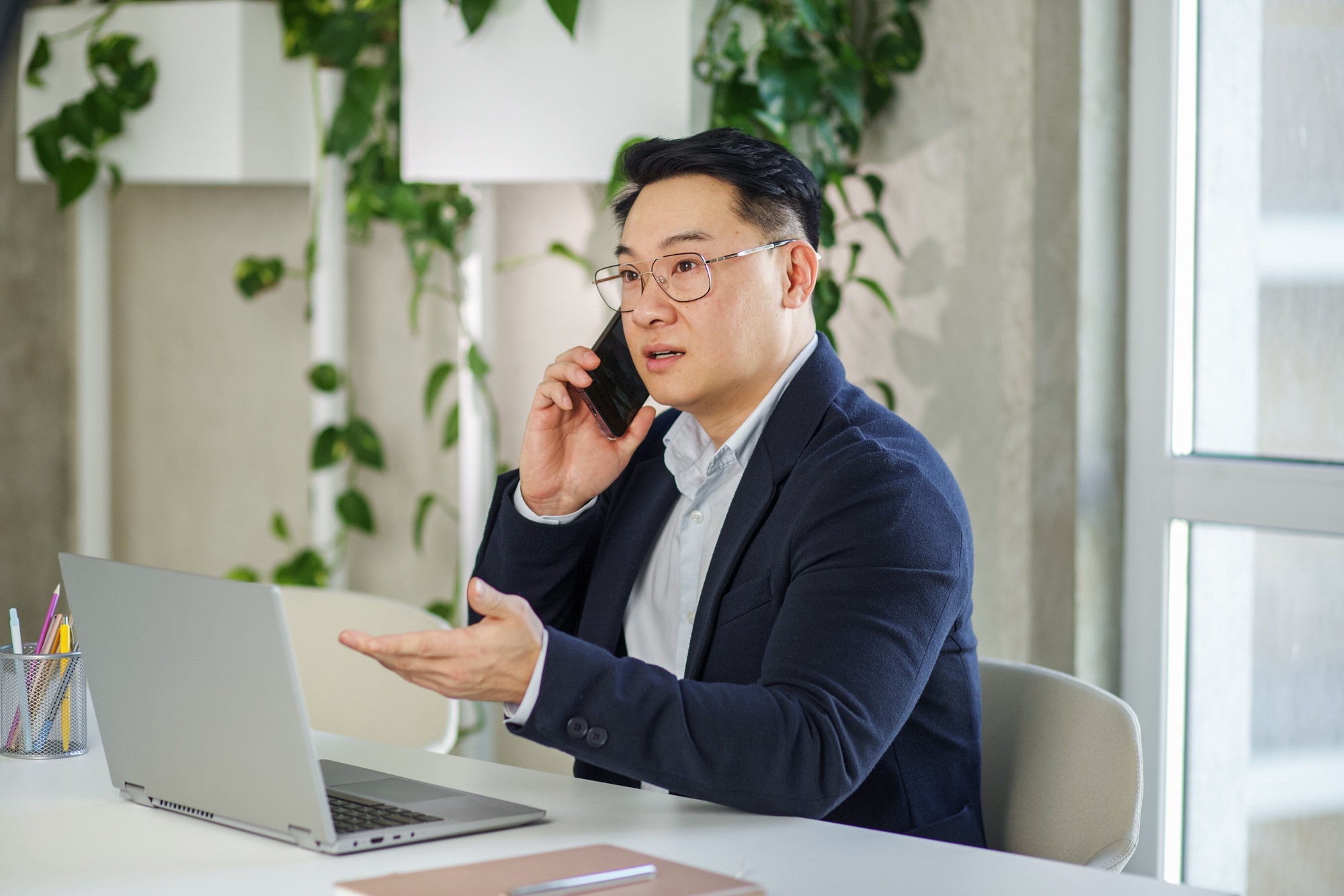 Asian businessman working in office, using laptop and smartphone. Human resources.