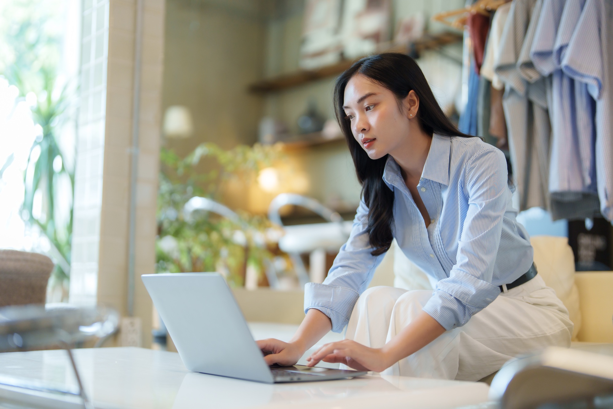 Asian businesswoman working on laptop in clothing store