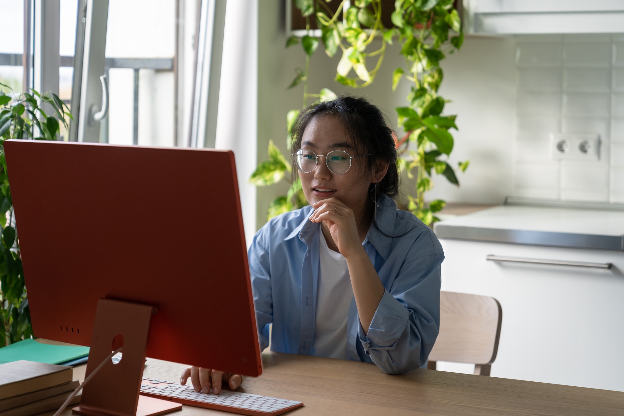 Asian girl looking at computer exploring free educational resources on internet, studying at home