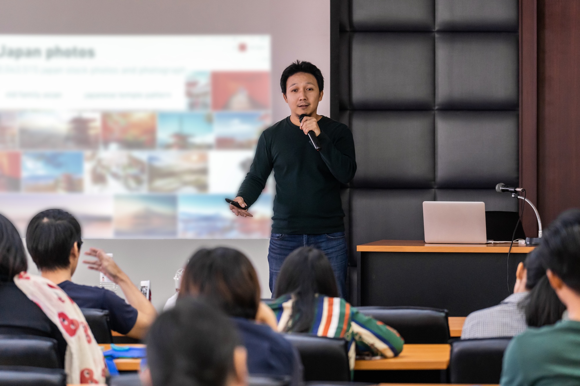 Asian Speaker or lecture with casual suit on the stage presenting via projector screen