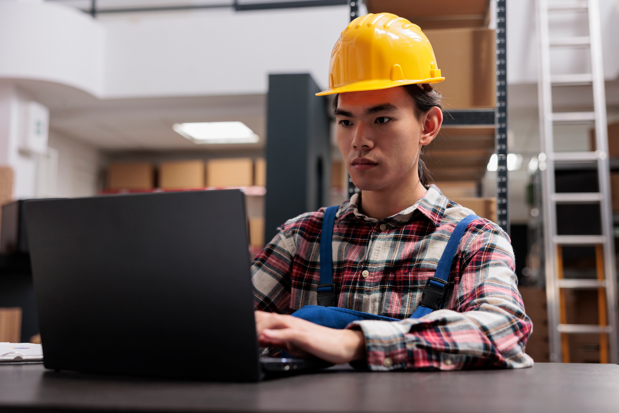 Asian warehouse employee controling inventory using goods storing software
