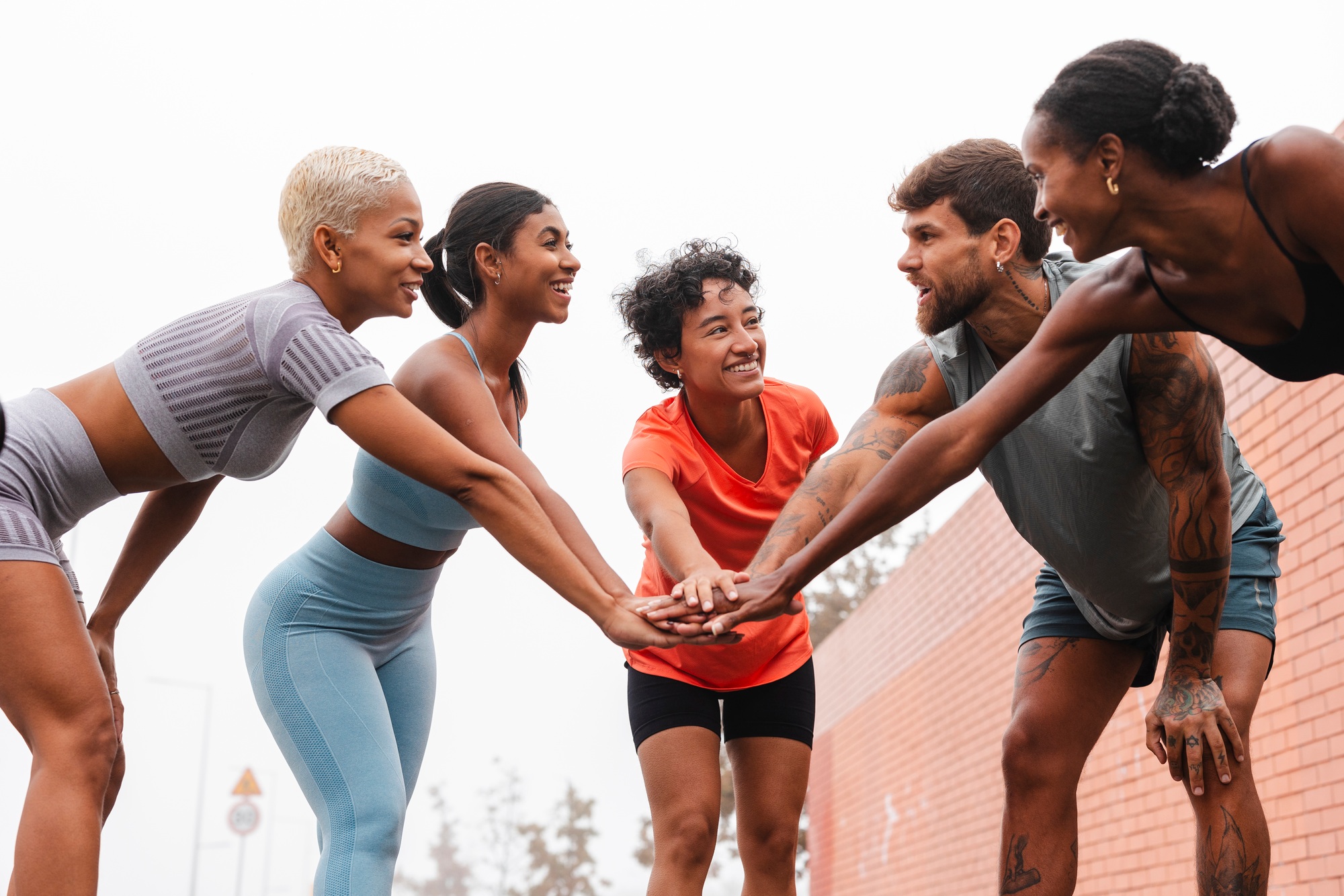 Athletes joining hands in urban setting, teamwork and fitness inspiration