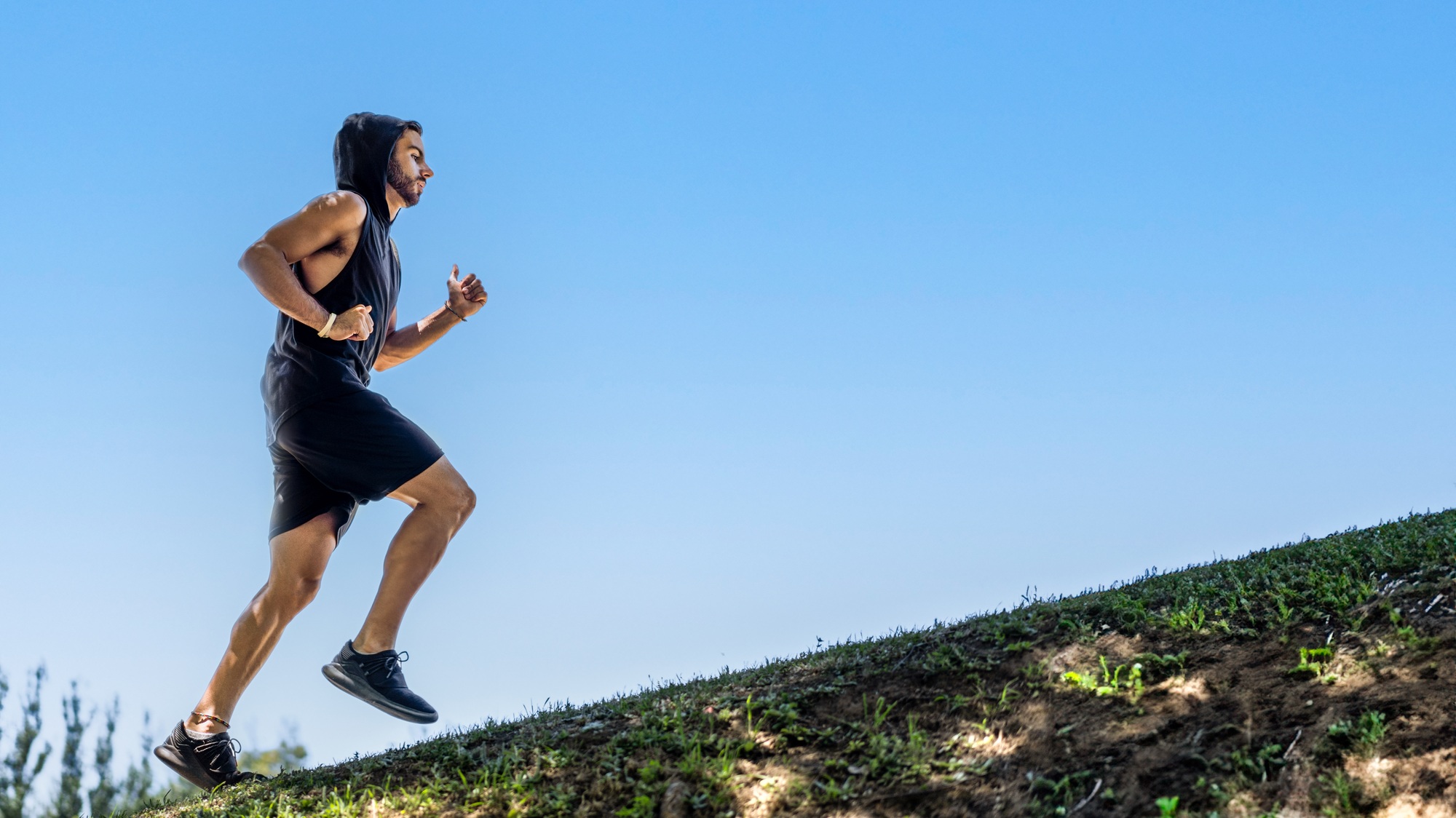 Athletic young man enjoying a challenging run on rolling terrain in a peaceful park setting.