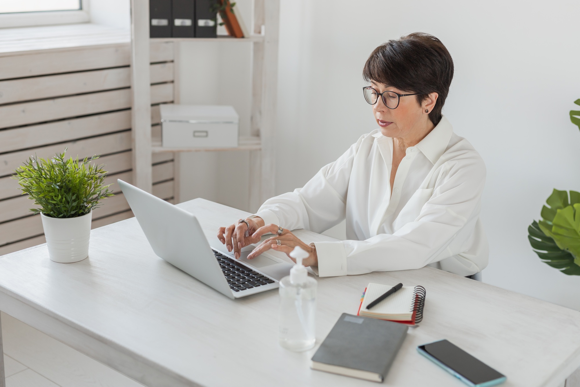 Attractive mature business woman working on laptop in her workstation - manager and office concept