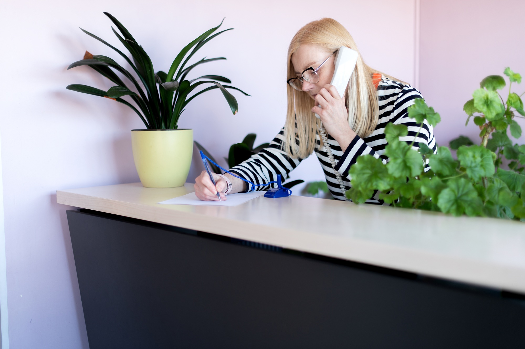 Attractive middle-aged woman talks on phone at her workplace
