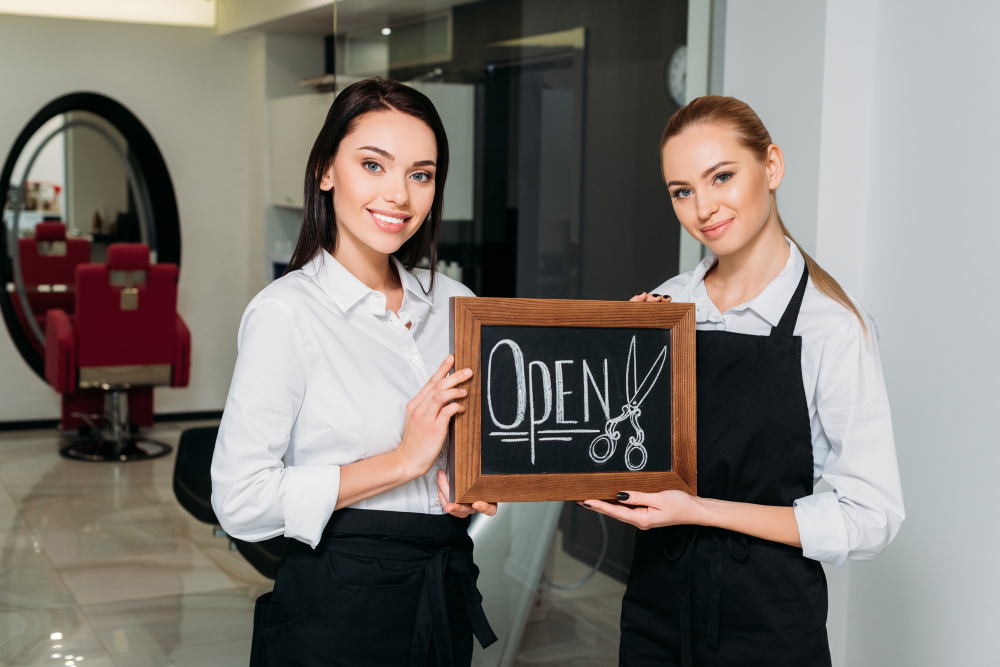 attractive proprietors standing with signboard open