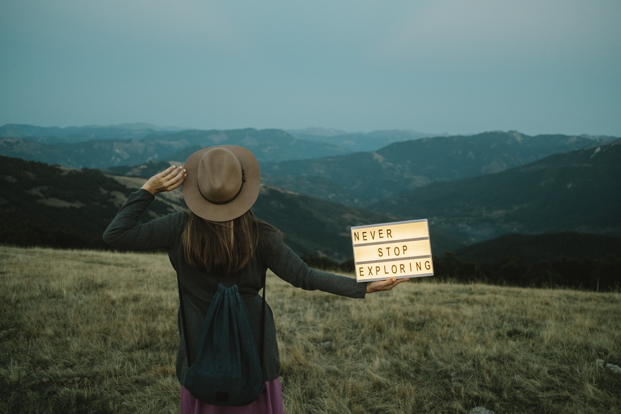 Back of woman with Box with text never stop exploring