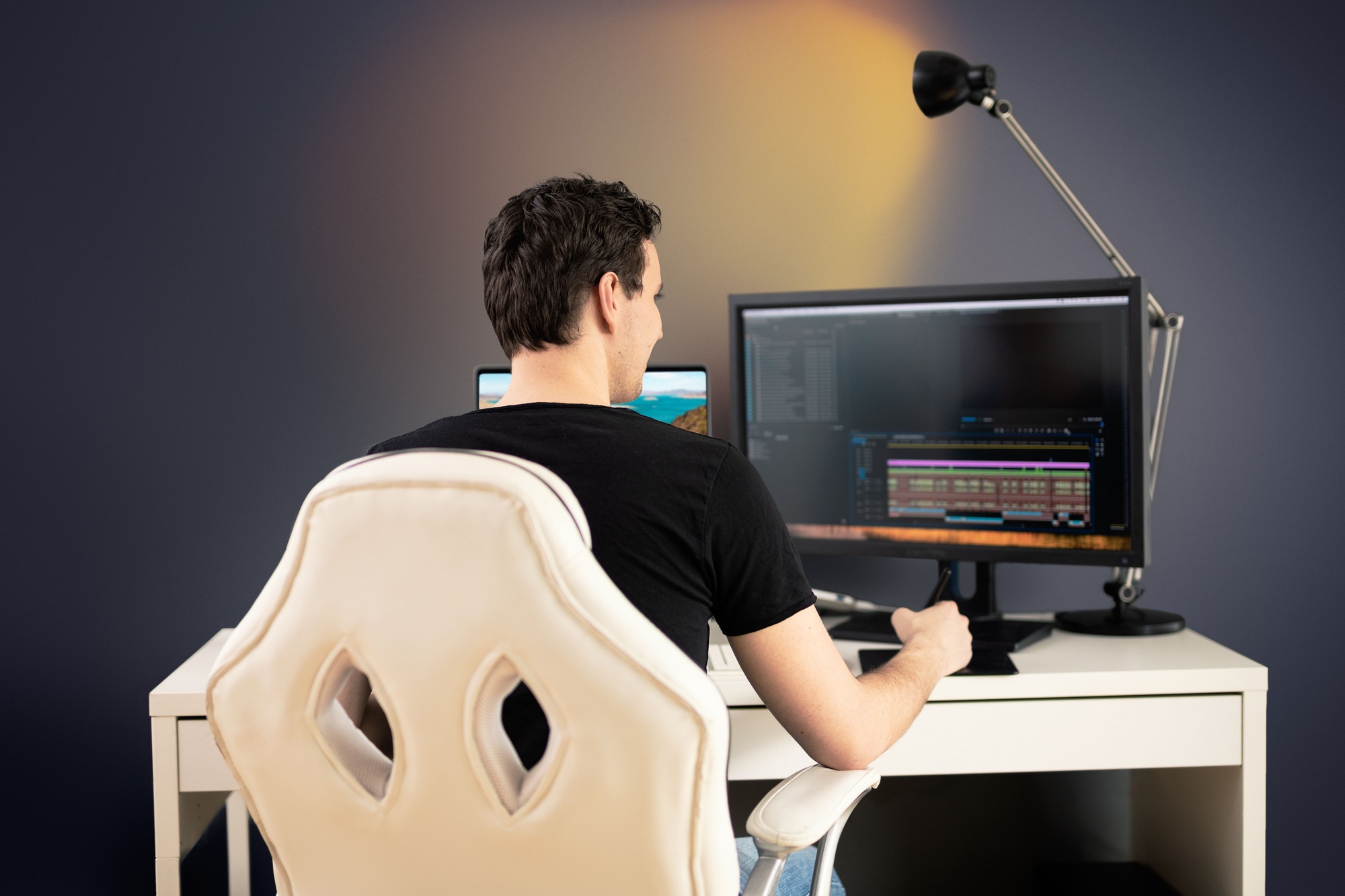 Back view of a young man editing some video footage on his computer in his office