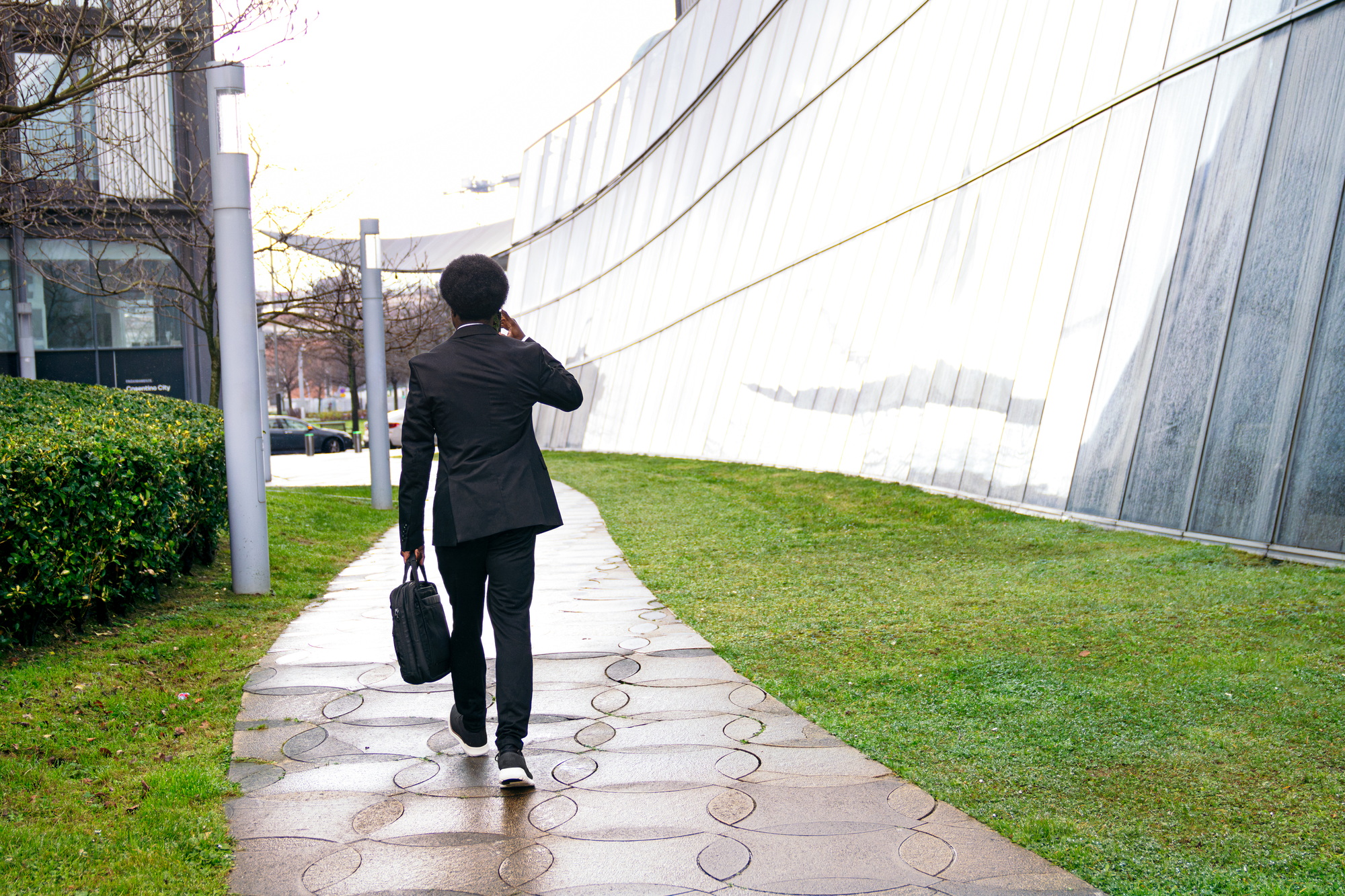 Back View of African Businessman Walking in City on Phone