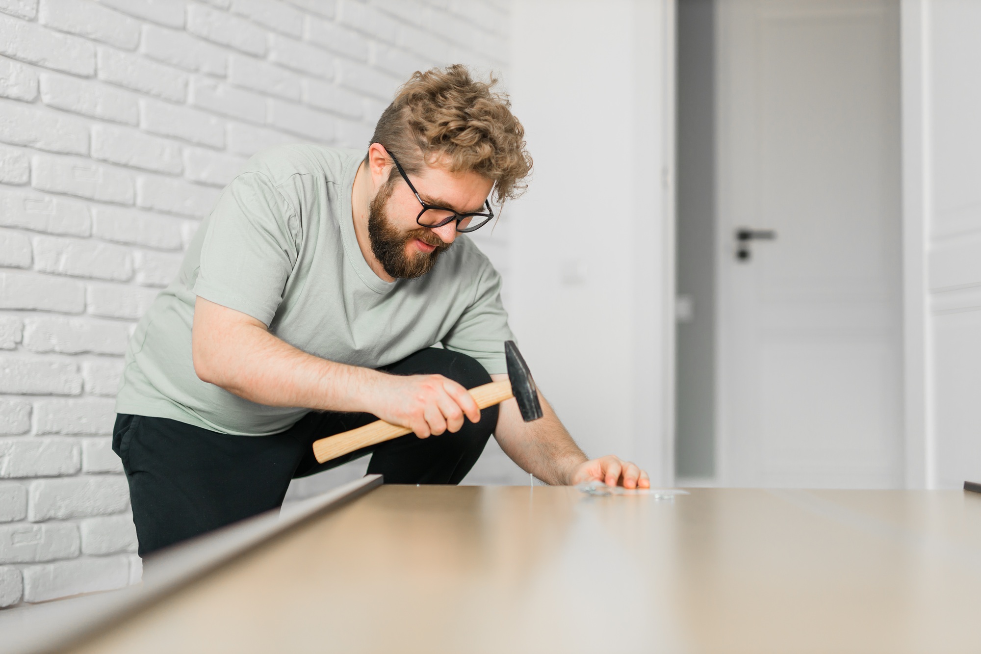 Bearded millennial man assemble his bookcase. He uses tools for furniture. Furniture for the