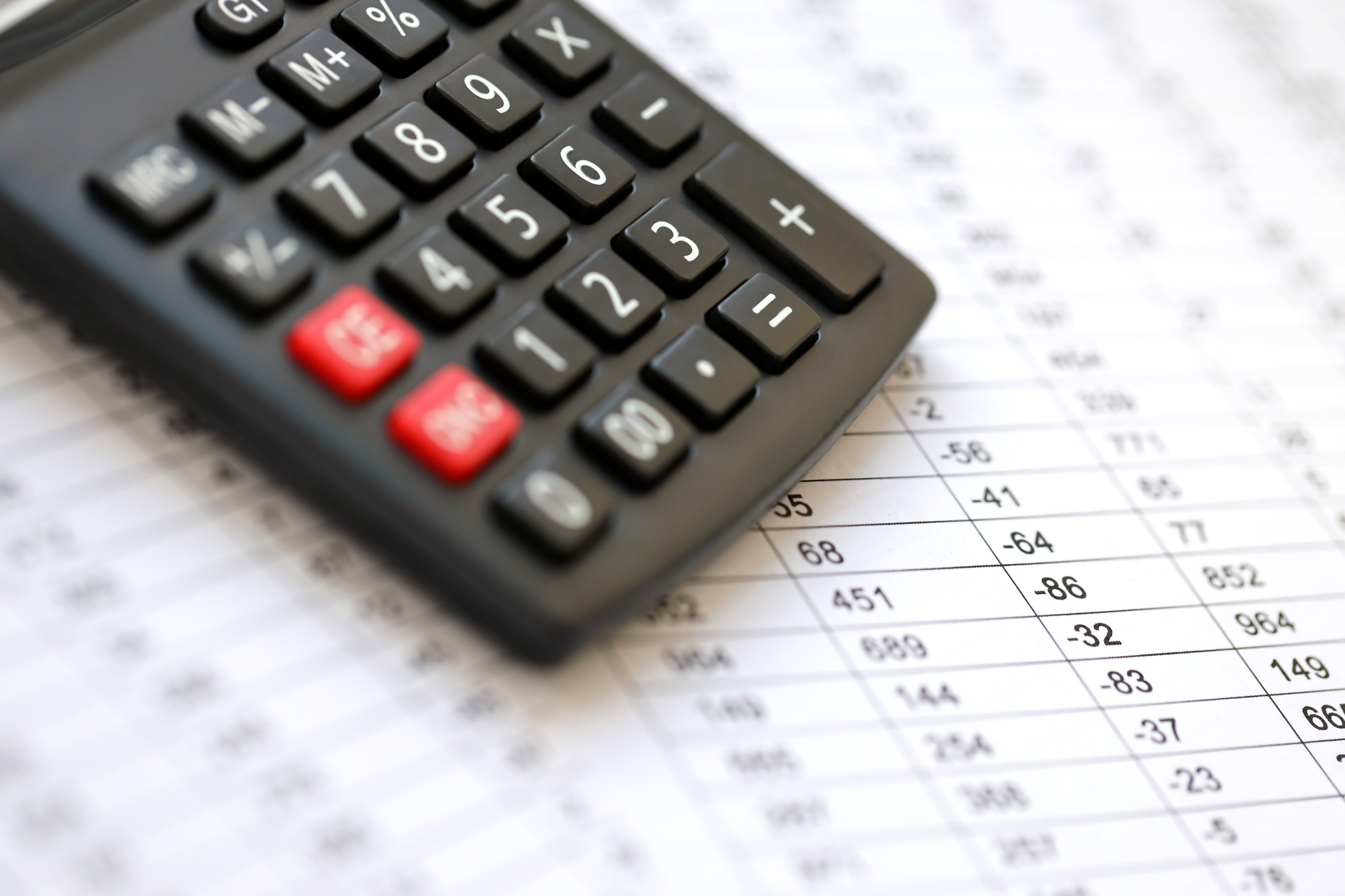 Big black calculator lies on financial statement and balance sheeet on desk of auditor close up