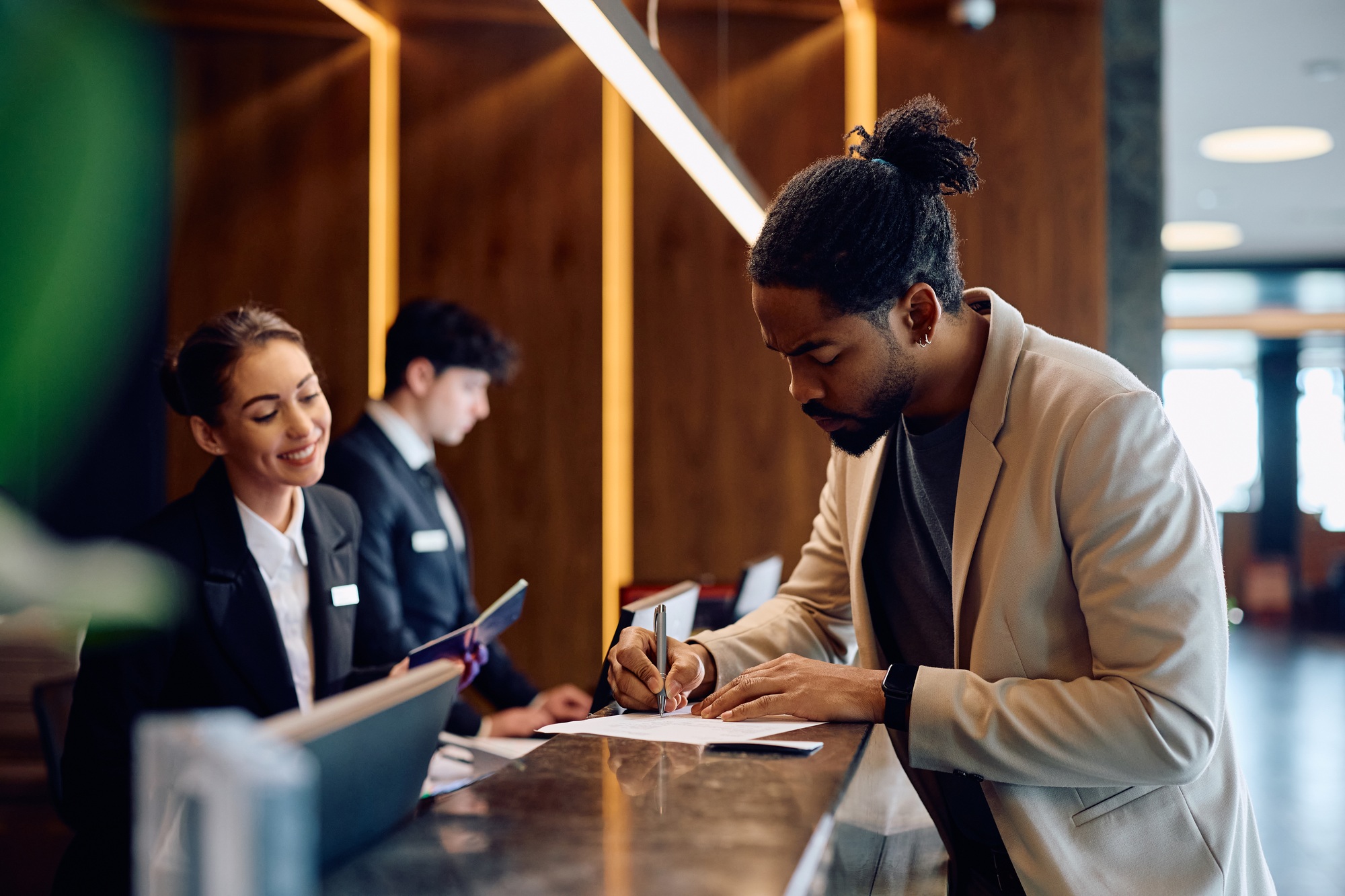 Black filing registration paperwork at hotel front desk.