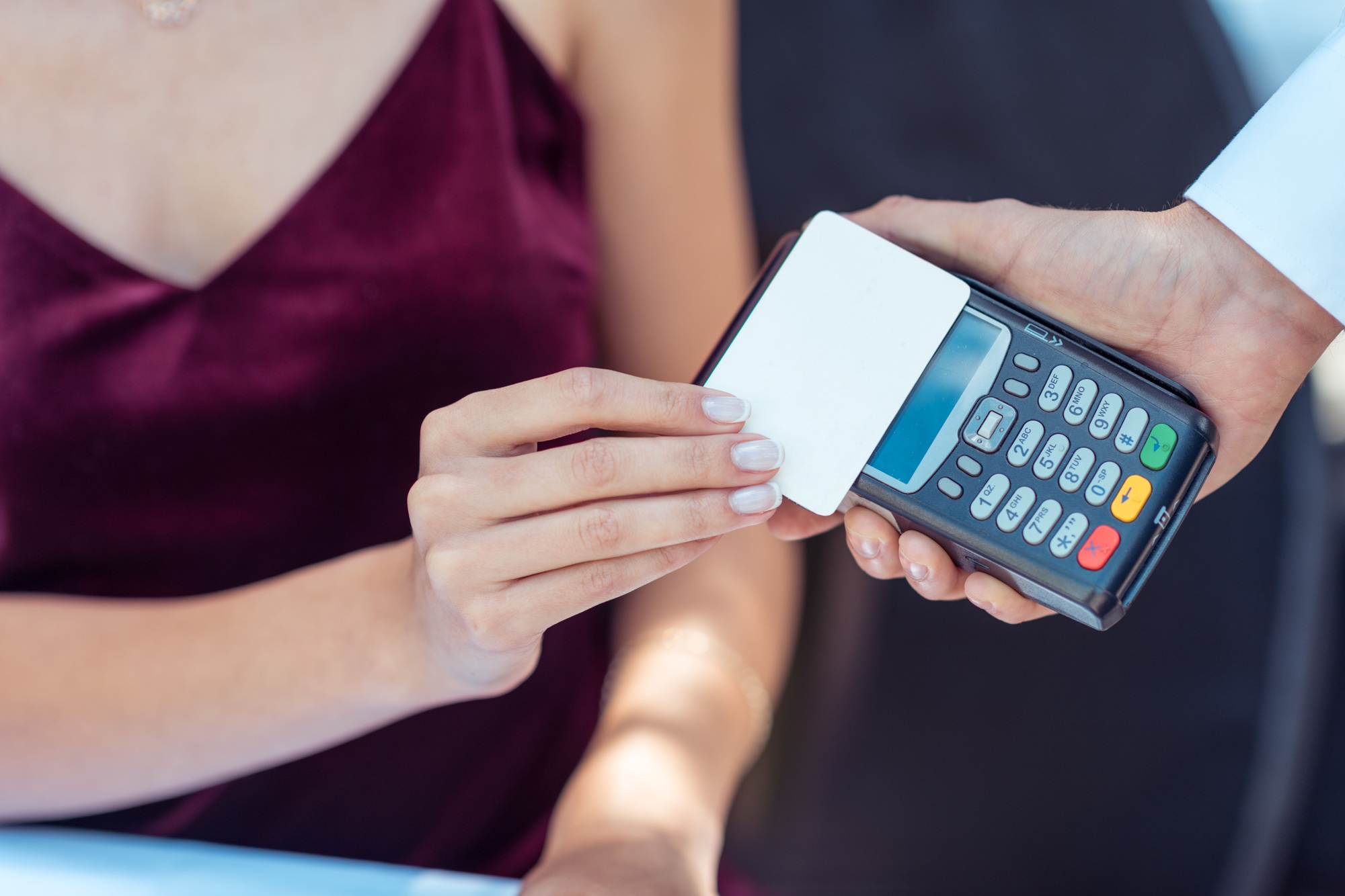 Close-up view woman using contactless credit card on pos terminal