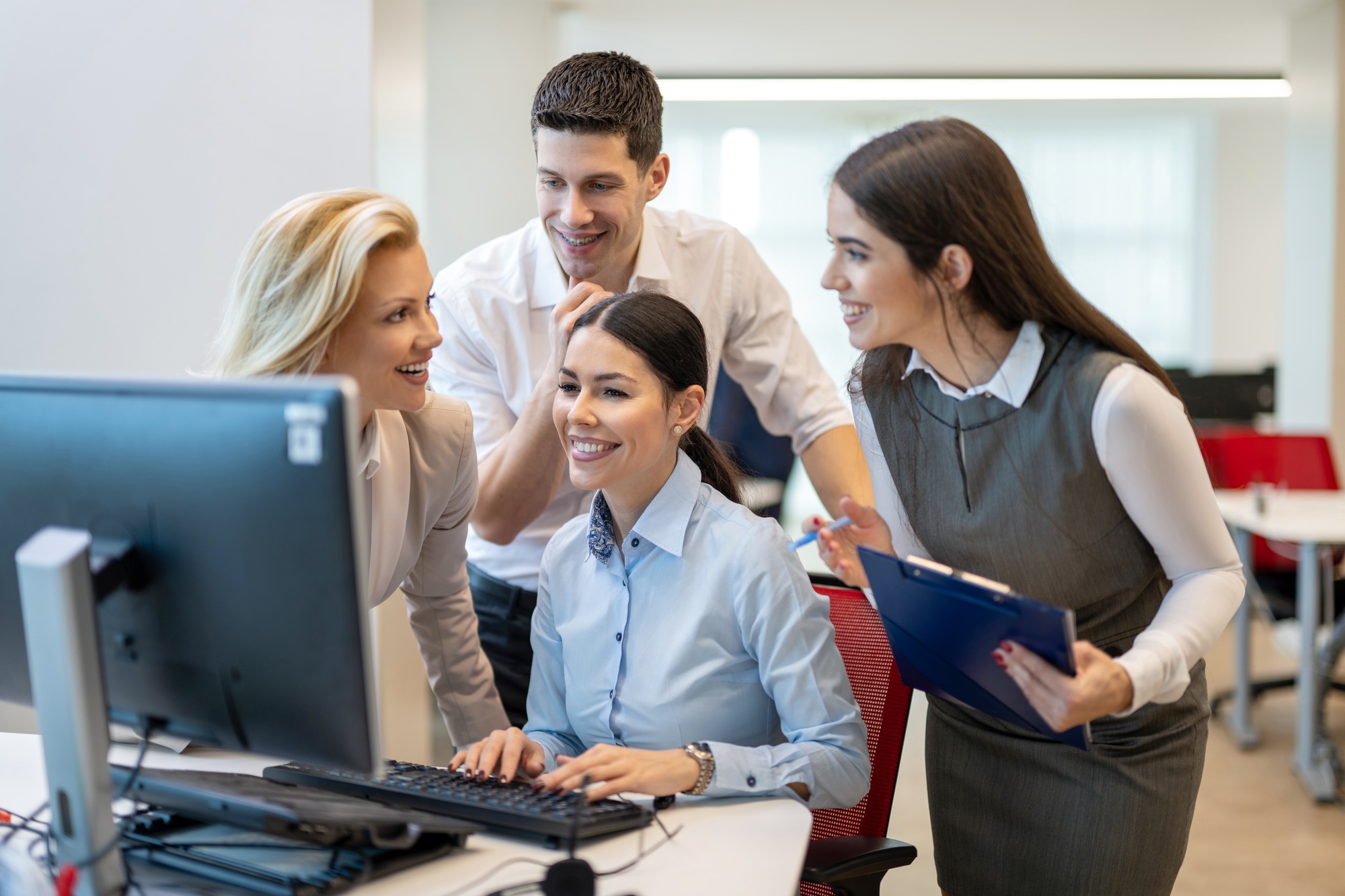 Business people interacting with each other and discussing business project at computer in office.