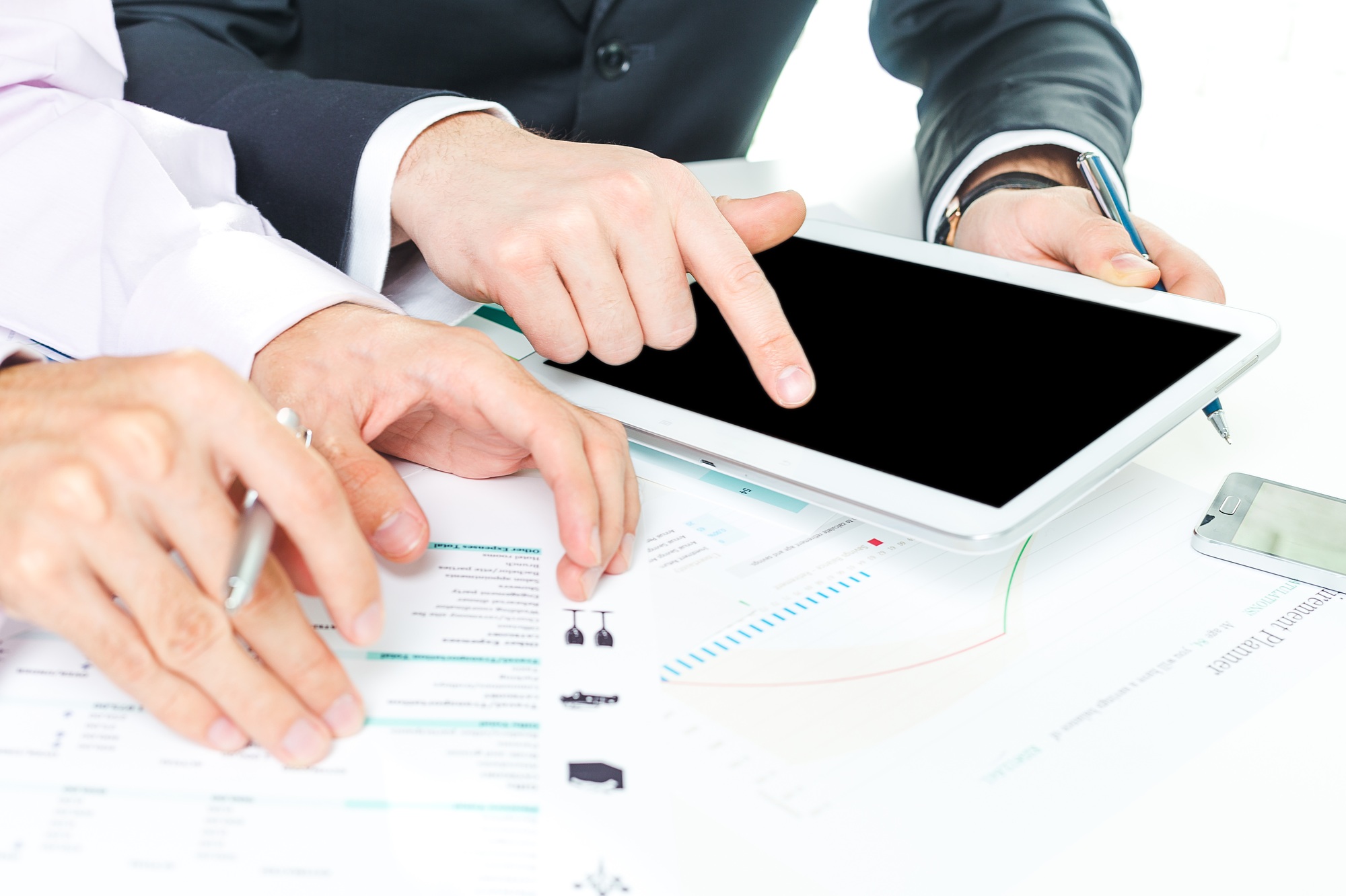 Business team collaborates on tablet while reviewing documents in a modern office environment