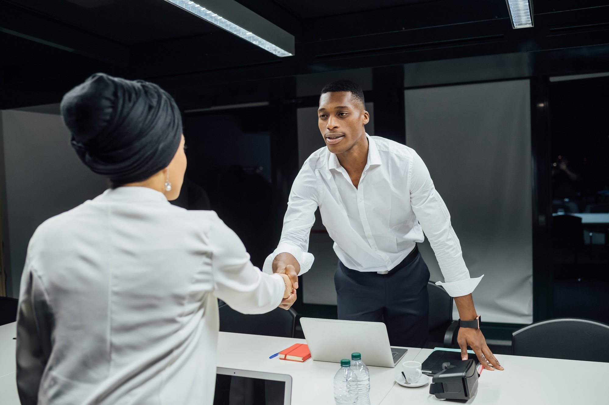 Businessman and woman shaking hands over conference table