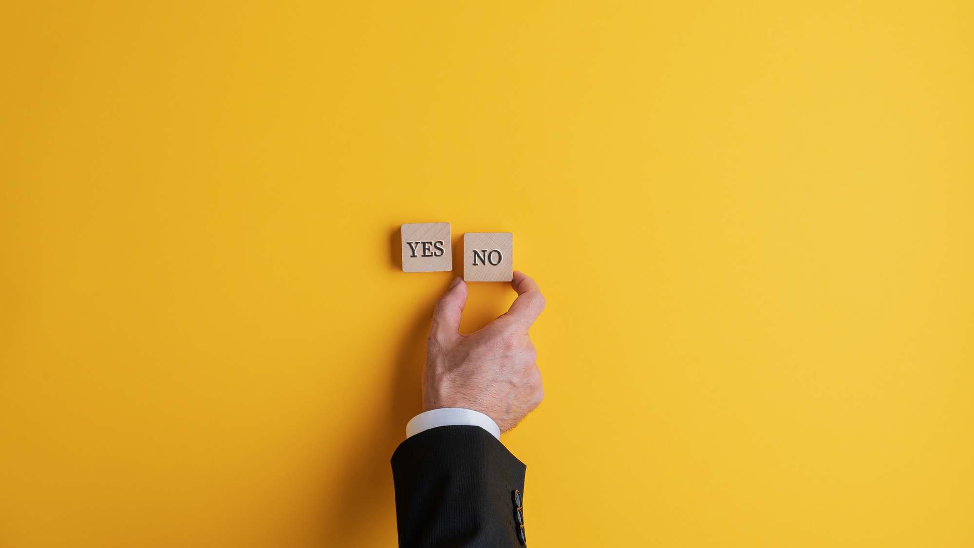 Businessman placing two wooden blocks with Yes and No words