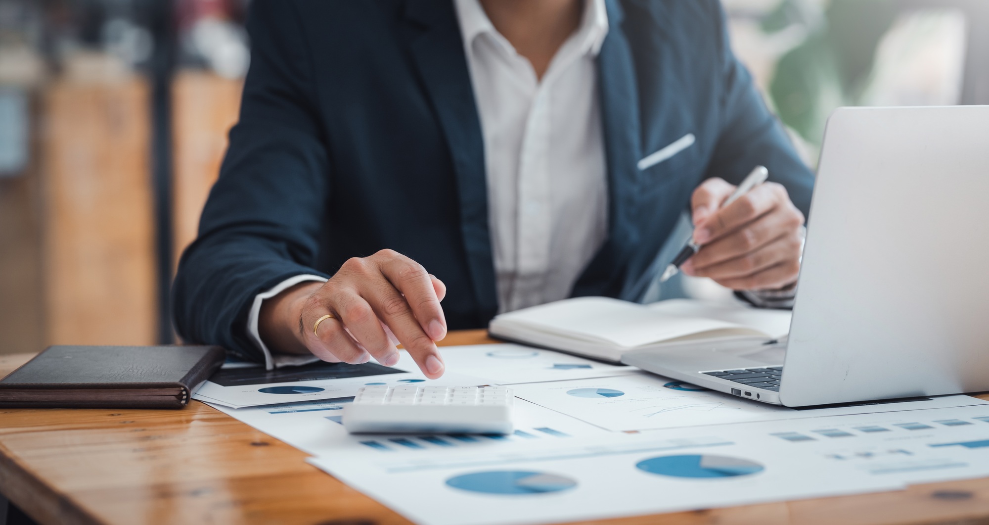 Businessman using calculator and laptop for financial analysis and investment planning.