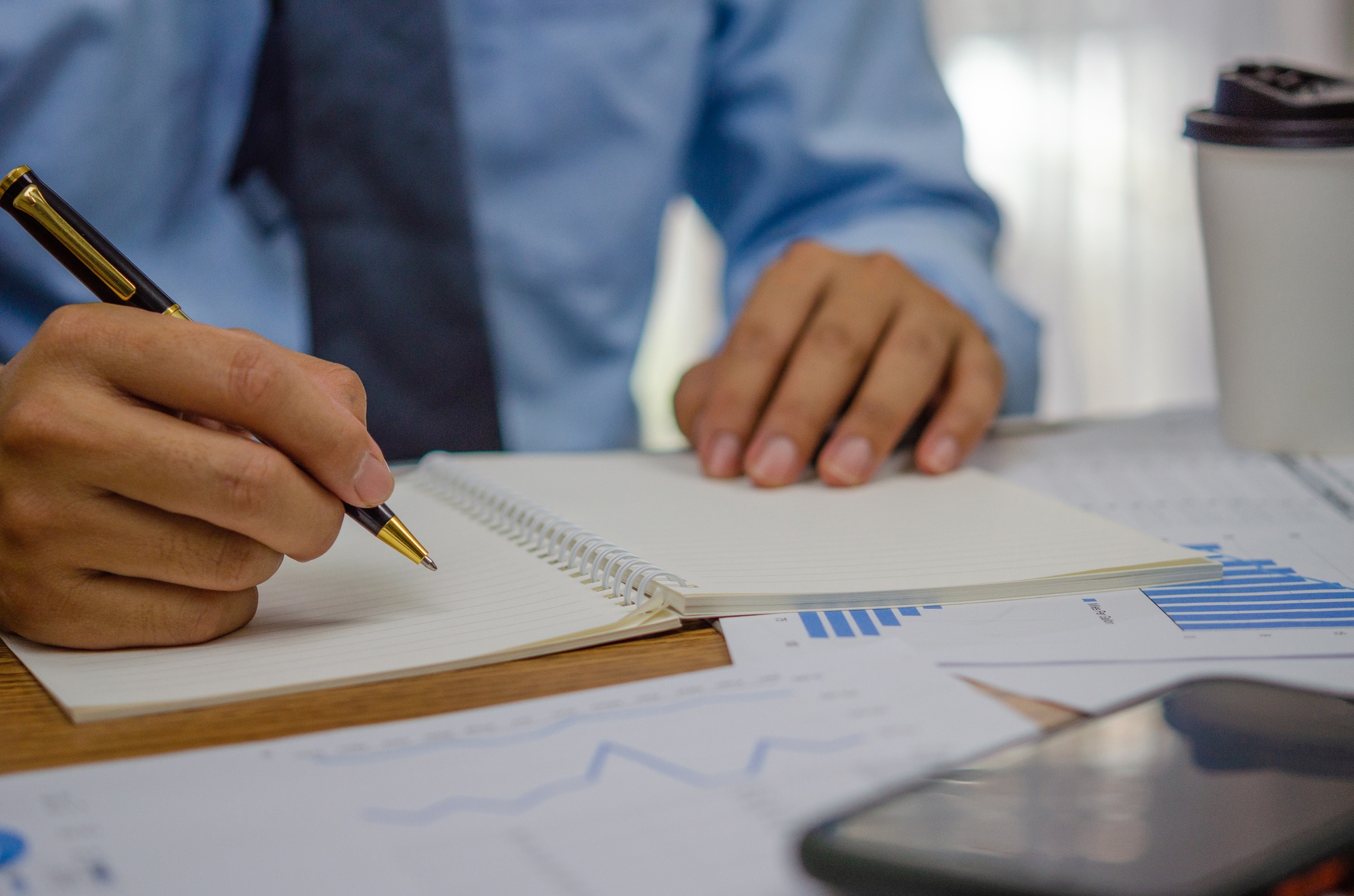 Businessman using pen writing note book planning journal and analysis