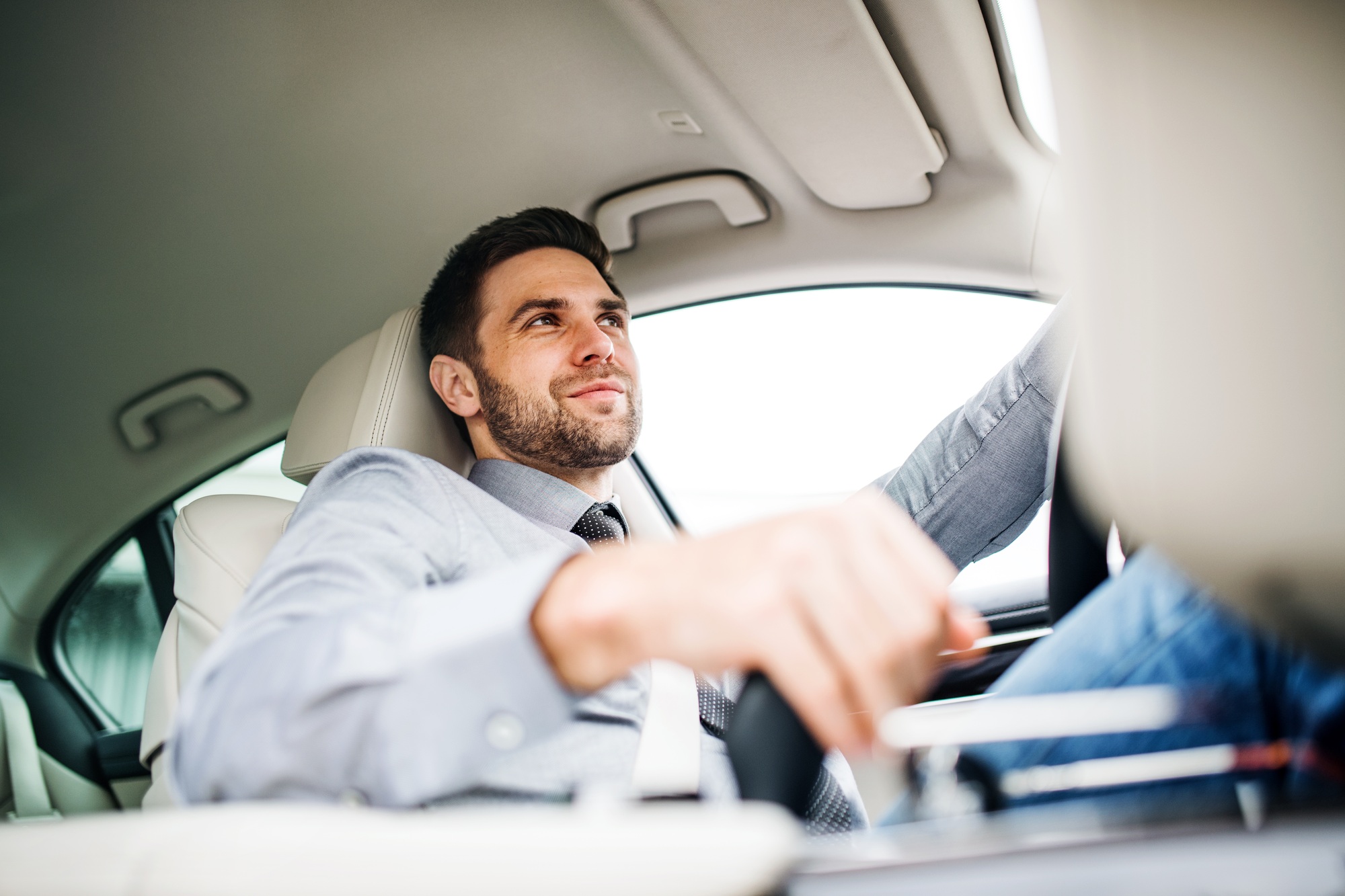 Businessman with shirt and tie sitting in brand new car, driving
