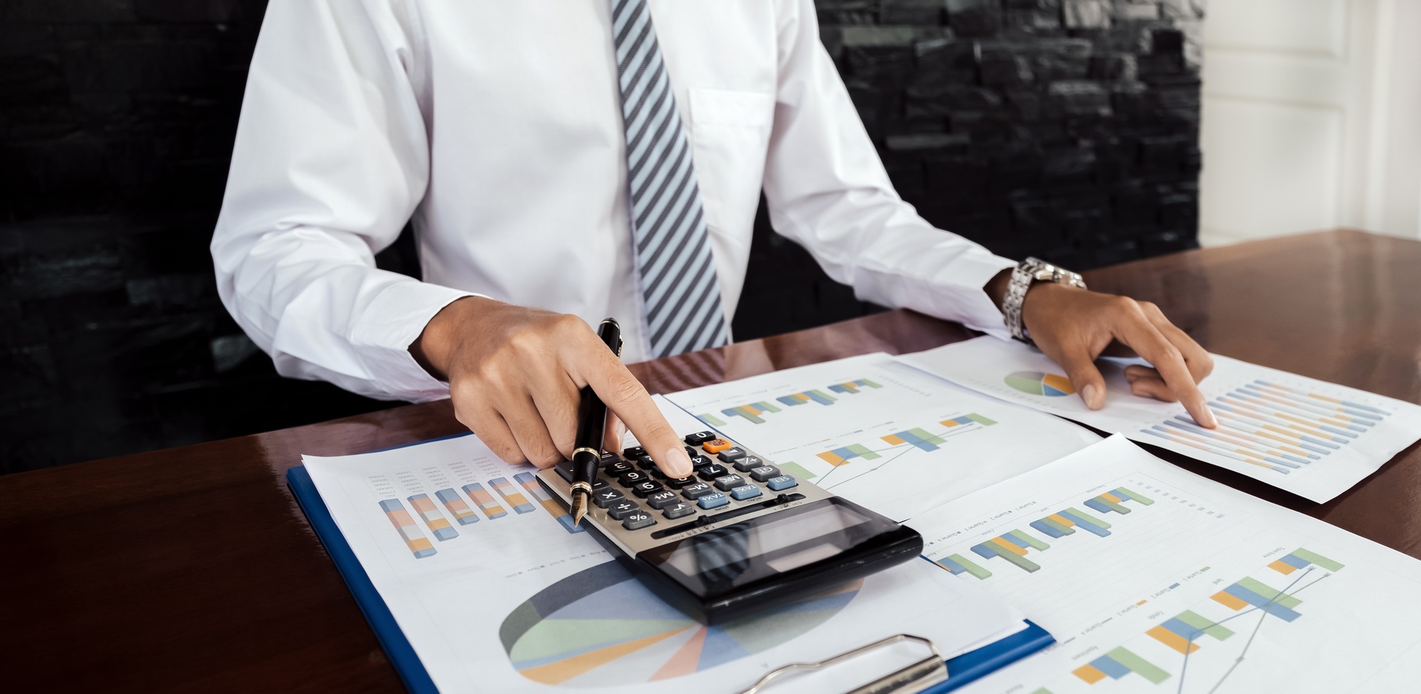 Businessmen bookkeeper hand holding pen use calculator analysis the business graph
