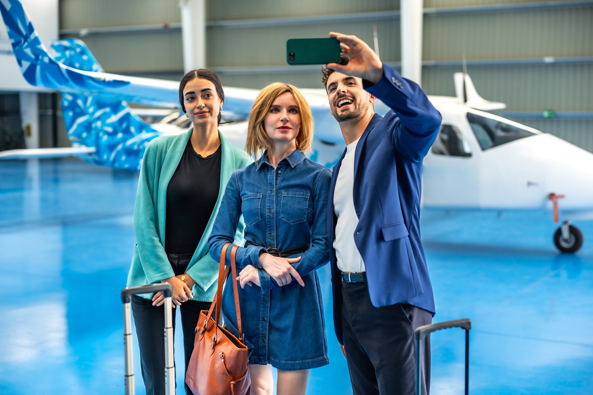 Businesspeople taking selfie in hangar with private jet