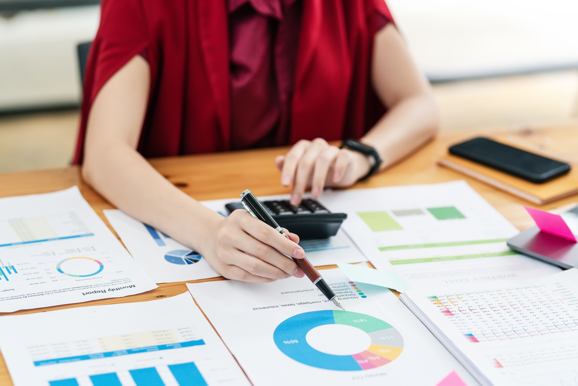 businesswoman holding a pen and pointing at a graph chart using calculation