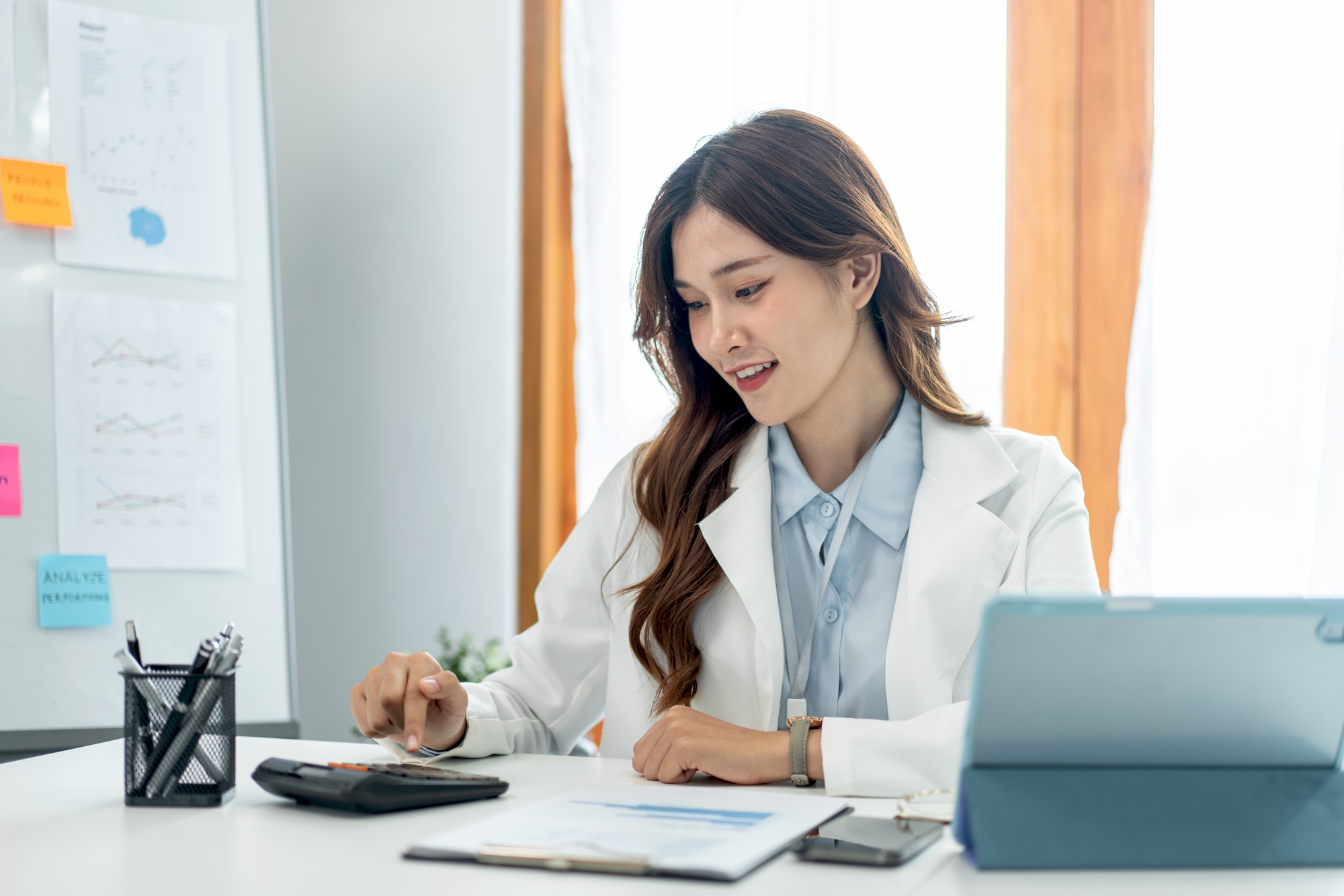 Businesswoman is using calculator to calculate cost and income of business while working to analysis