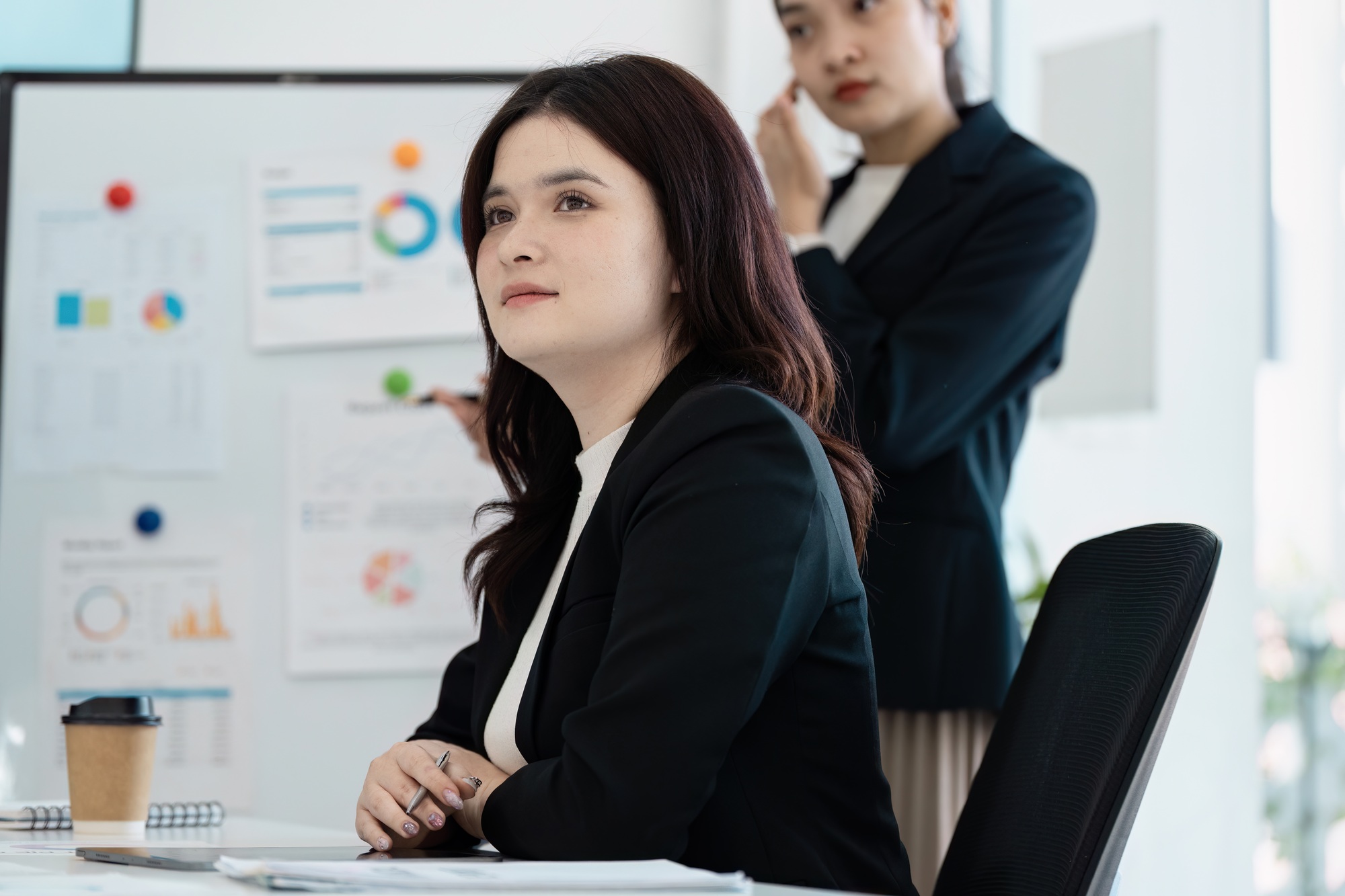 Businesswoman listening thoughtfully during a corporate presentation.