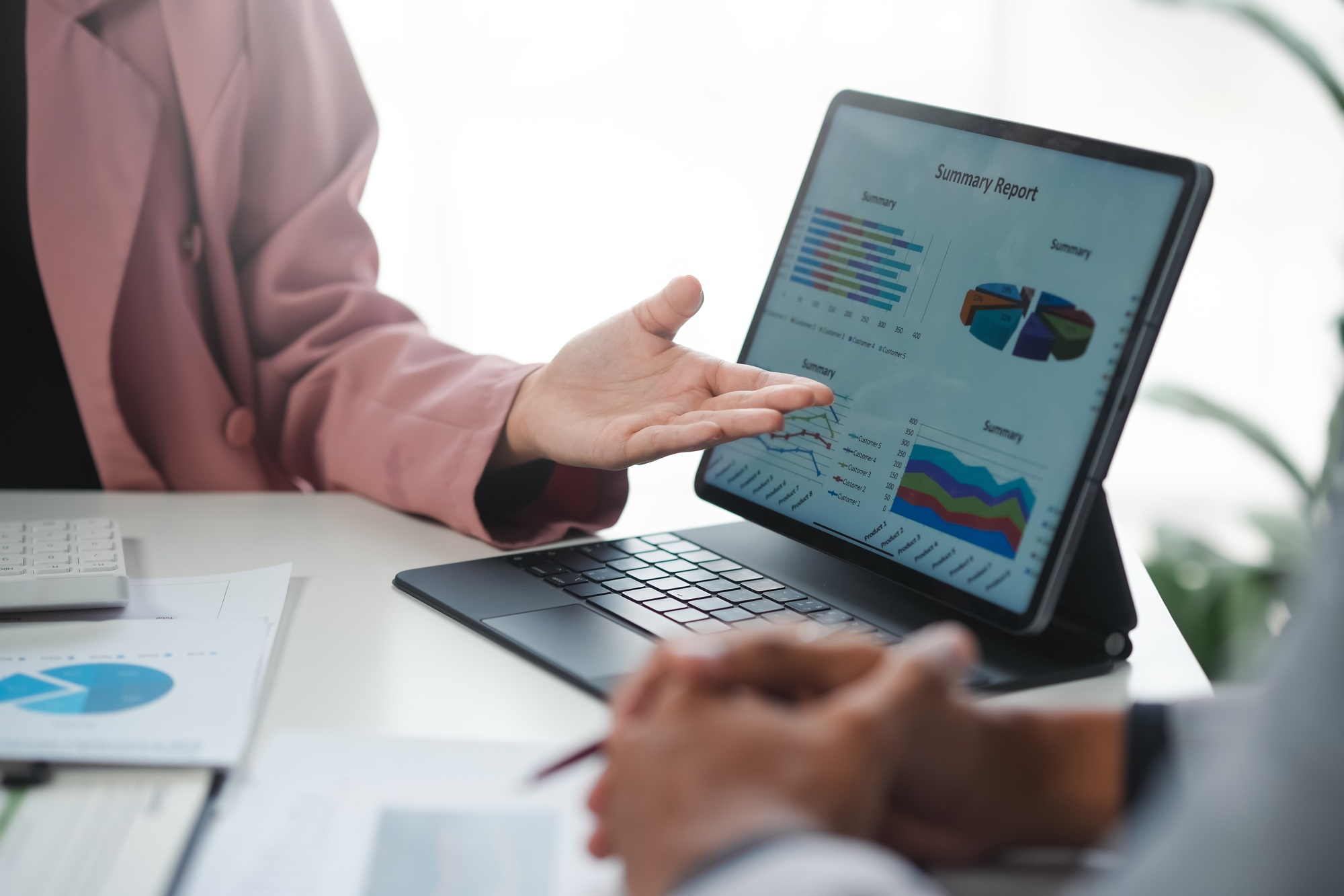 Businesswoman presenting financial summary report on tablet to colleague