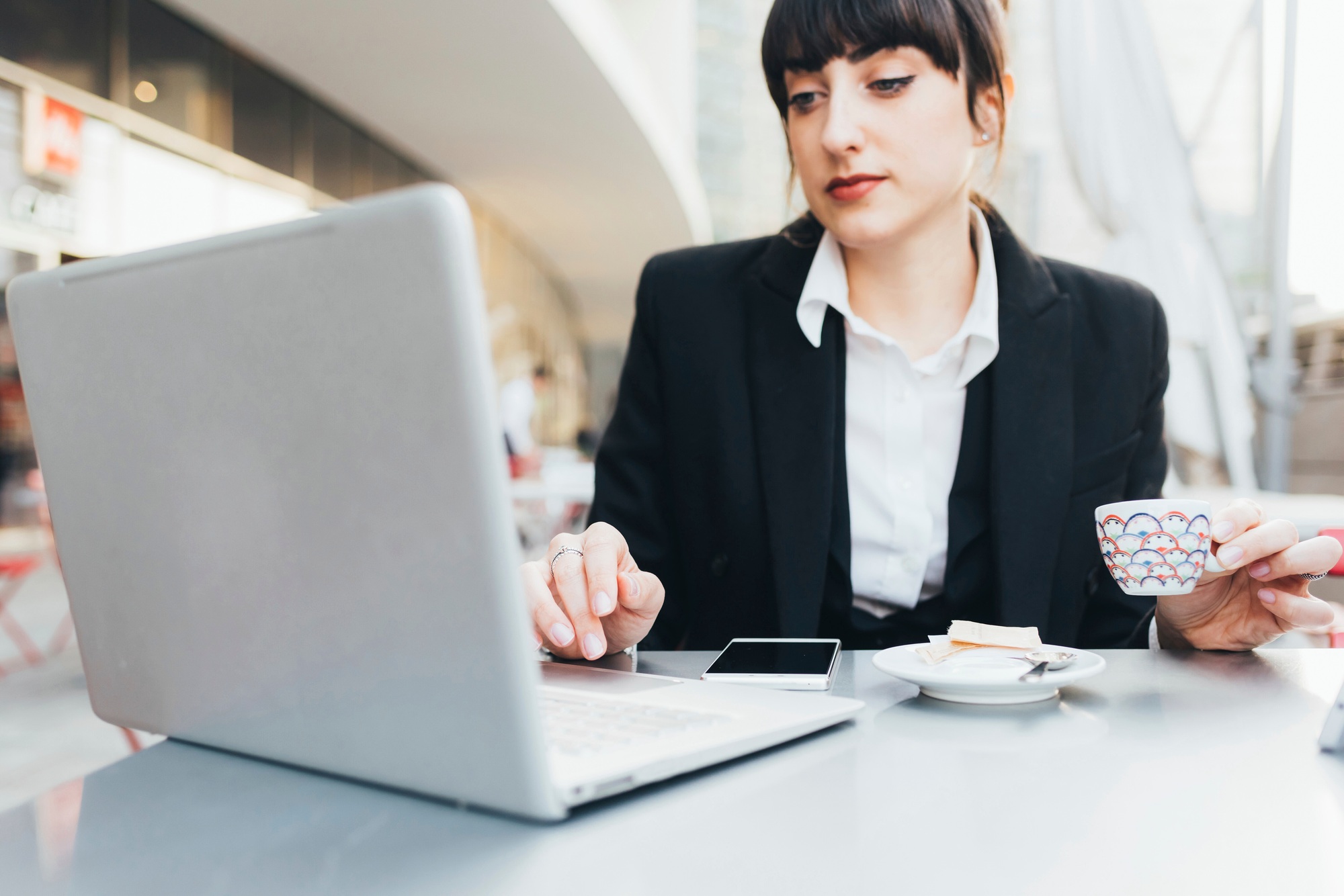 Businesswoman using laptop in coffee shop, Milan, Italy